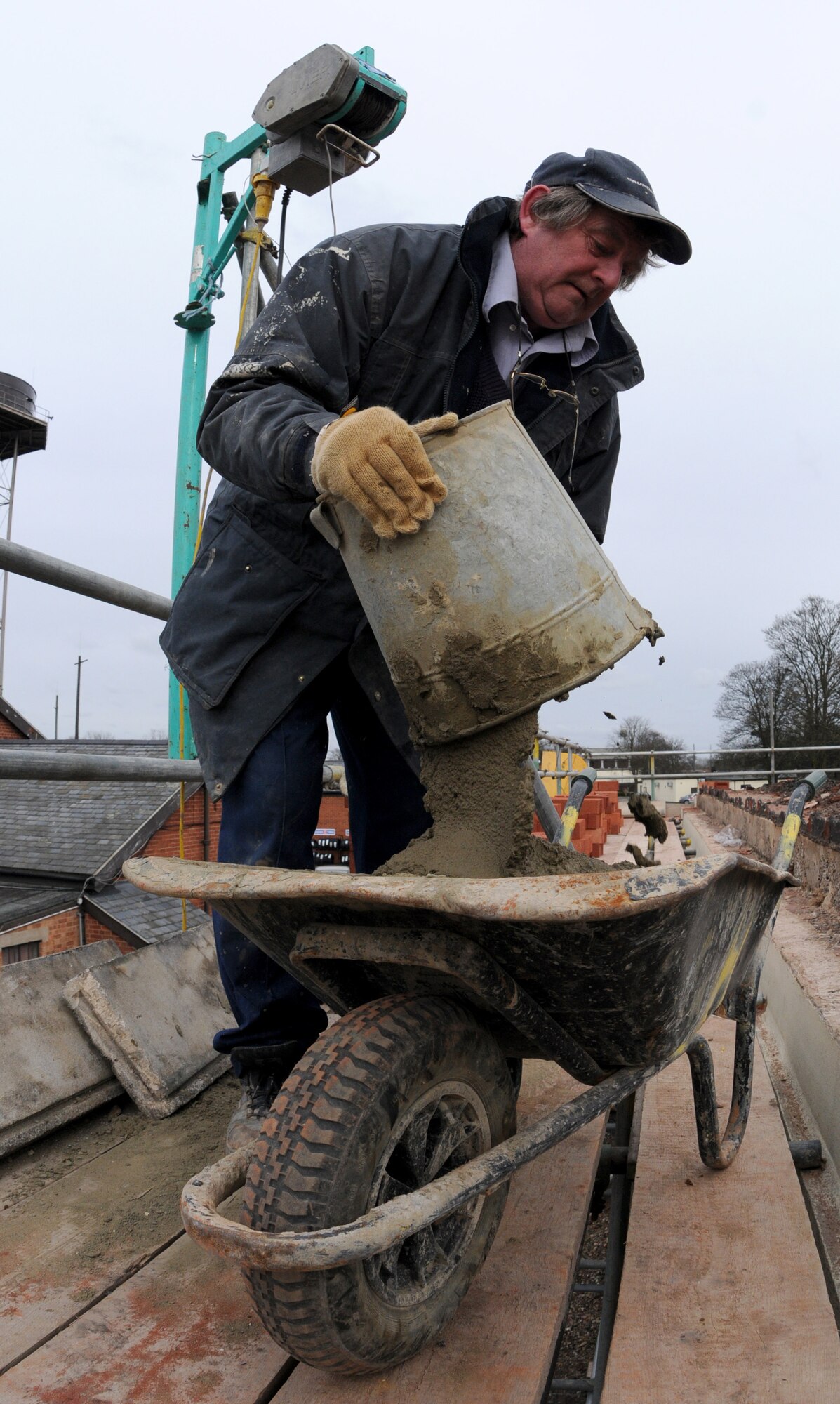 RAF MILDENHALL, England – Dave Garrett, a contracted mason worker, pours cement into a wheelbarrow during a reroofing project on top Building 514 March 3. The cement is applied and each individual brick is hand-laid, making precise measurements crucial to building a wall. (U.S. Air Force photo/ Staff Sgt. Jerry Fleshman)