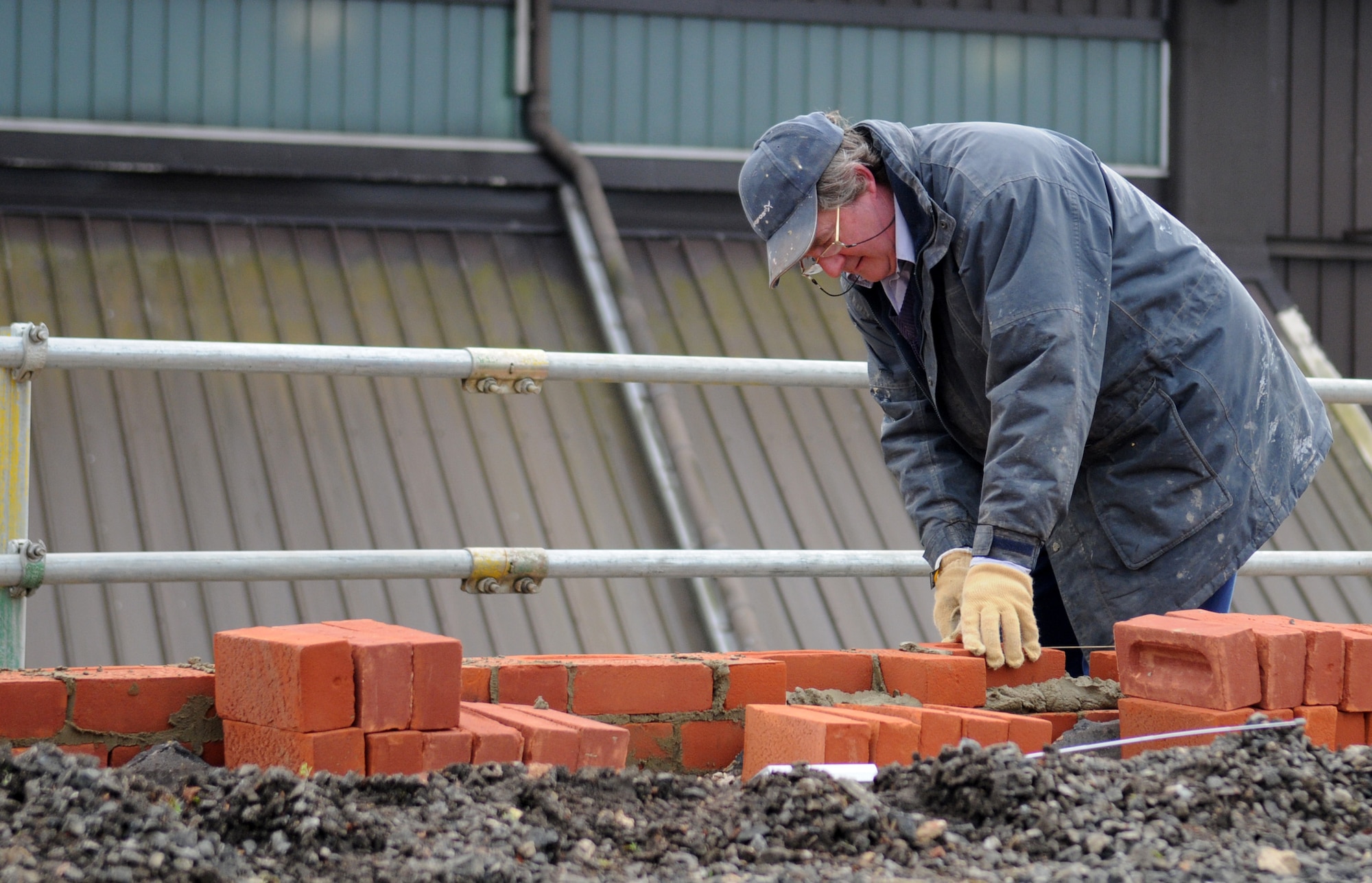 RAF MILDENHALL, England - Dave Garrett, a contracted mason worker, lines up a row of bricks on top of Building 514 as a part of a reroofing project March 3. (U.S. Air Force photo/ Staff Sgt. Jerry Fleshman)