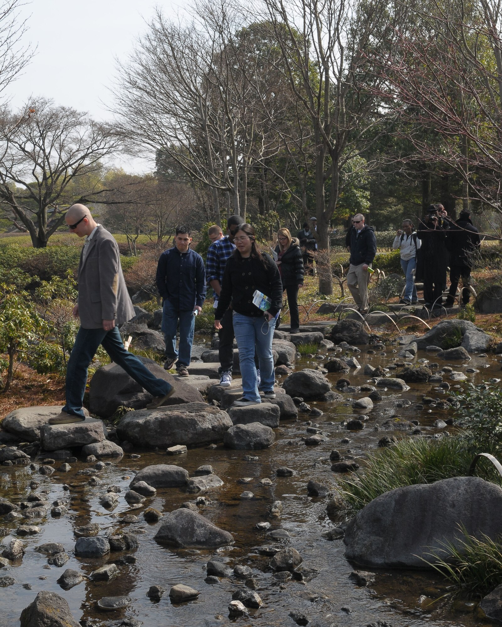 TACHIKAWA, Japan -- Members from Yokota Air Base walk across a stream Mar. 3 during a tour through the Japanese Garden at Showa Kinen Park. Park managers hosted the group of military and civilian residents of Yokota, to help them experience authentic Japanese culture. The Japanese government created Showa Park 1983 to commemorate the 50th anniversary of Emperor Showa's reign. (U.S. Air Force photo/Airman 1st Class Sean Martin)
