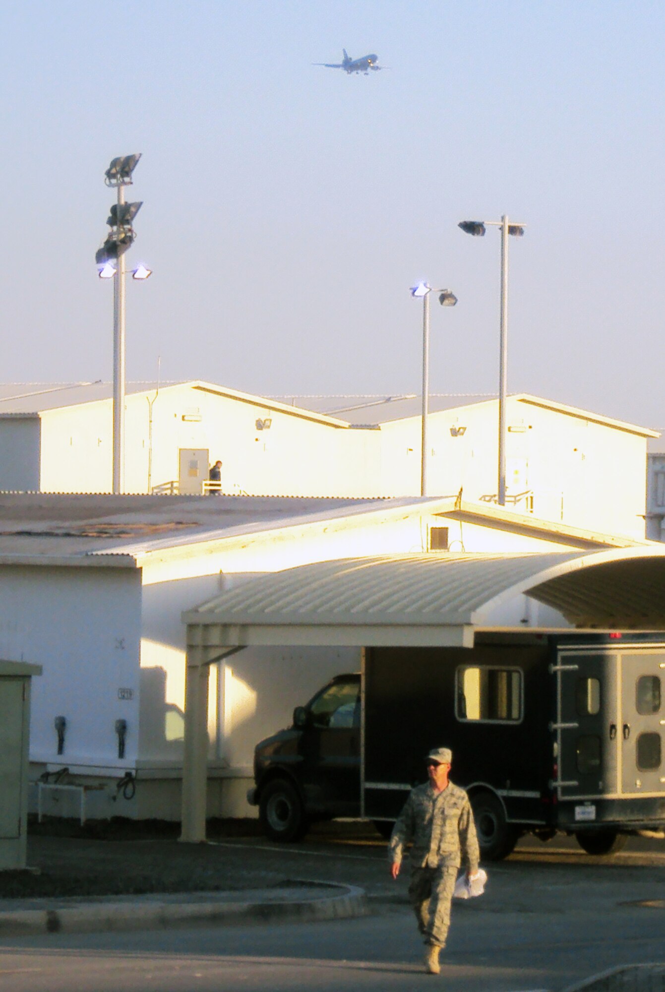 An Airmen walks through the compound of the 380th Air Expeditionary Wing while overhead a KC-10 Extender from the 908th Expeditionary Air Refueling Squadron returns from a combat air refueling mission at a non-disclosed base in Southwest Asia on March 4, 2010. The 380th AEW supports operations Iraqi Freedom and Enduring Freedom and the Combined Joint Task Force-Horn of Africa. (U.S. Air Force Photo/Master Sgt. Scott T. Sturkol)
