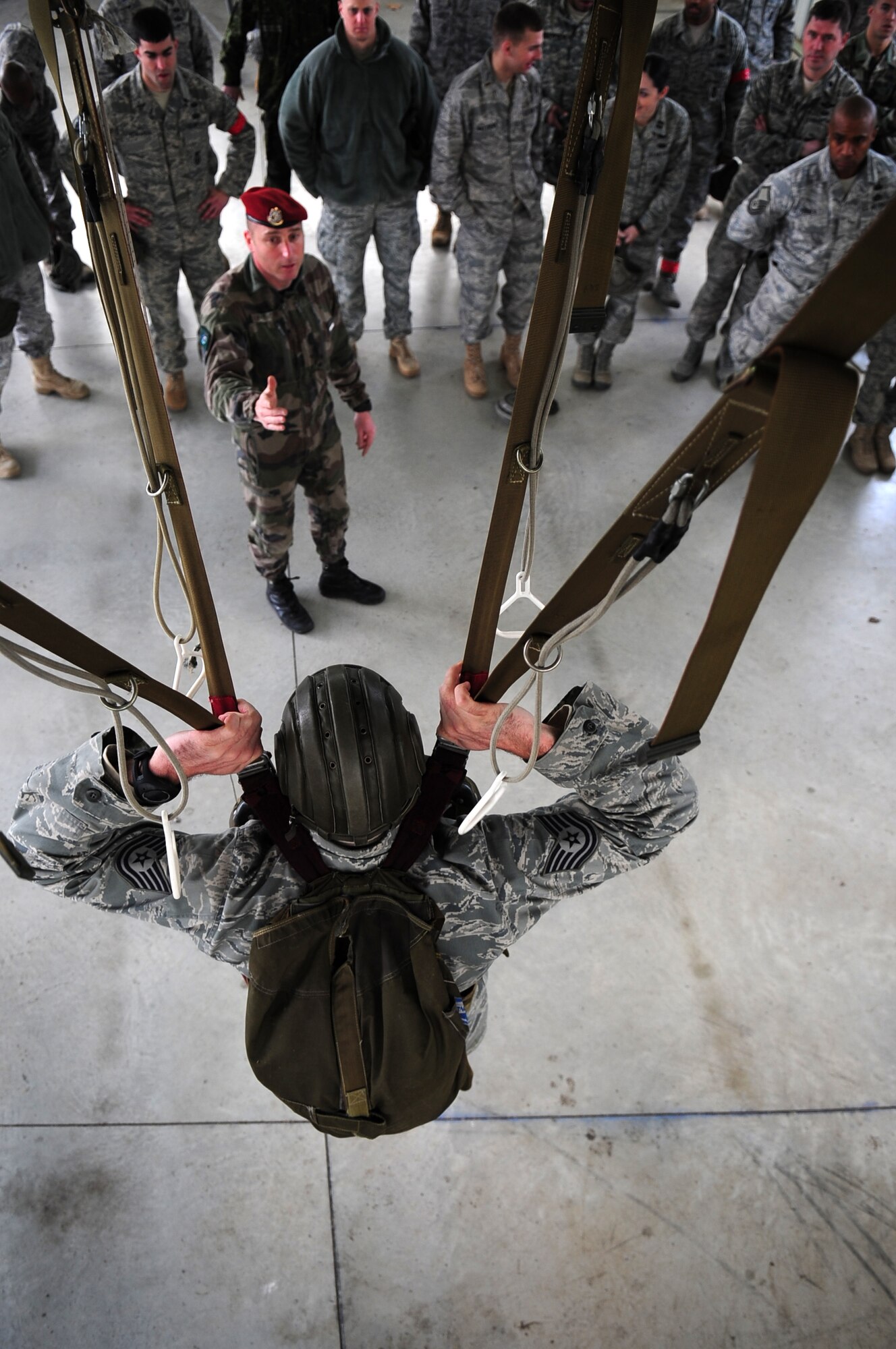 French Airborne Academy instructor Master Sgt. Stephane Paternotte, instructs U.S. military members on proper body position while in a French parachute, using U.S. Air Force Tech. Sgt. Jason Shaffer as an example in simulated equipment durring training before a combined nation jump, March 3, 2010. Members of the 435th Contingency Response Group and the 5th Quartermaster Company joined with their French military counterparts for a week of training at the École des troupes aéroportées (ETAP), or School of Airborne Troops, a military school dedicated to training the military paratroopers   of the French army, located in the town of Pau, in the département of Pyrénées-Atlantiques, France.  The ETAP is responsible for training paratroopers, and for international cooperation and promotion of paratroop culture. (U.S. Air Force Photo by Staff Sgt. Jocelyn Rich)