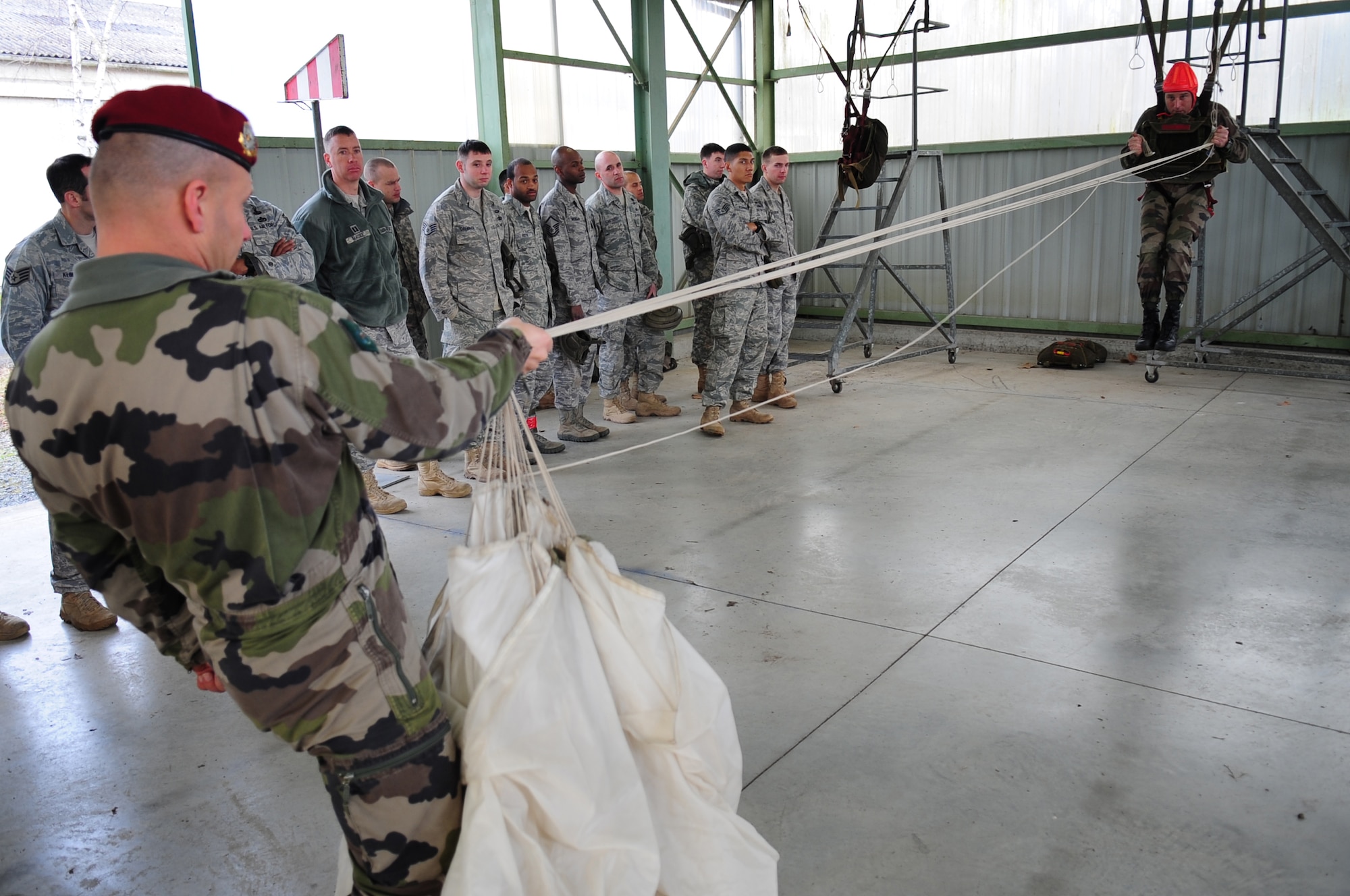 French Airborne Academy Master Sergeants Loic Neveu and Stephane Paternotte demonstrate proper procedure for paratroopers using French military equipment to members of the U.S. military before a combined nation jump, March 3, 2010.  Members of the 435th Contingency Response Group and the 5th Quartermaster Company joined with their French military counterparts for a week of training at the École des troupes aéroportées (ETAP), or School of Airborne Troops, a military school dedicated to training the military paratroopers   of the French army, located in the town of Pau, in the département of Pyrénées-Atlantiques, France.  The ETAP is responsible for training paratroopers, and for international cooperation and promotion of paratroop culture. (U.S. Air Force Photo by Staff Sgt. Jocelyn Rich)