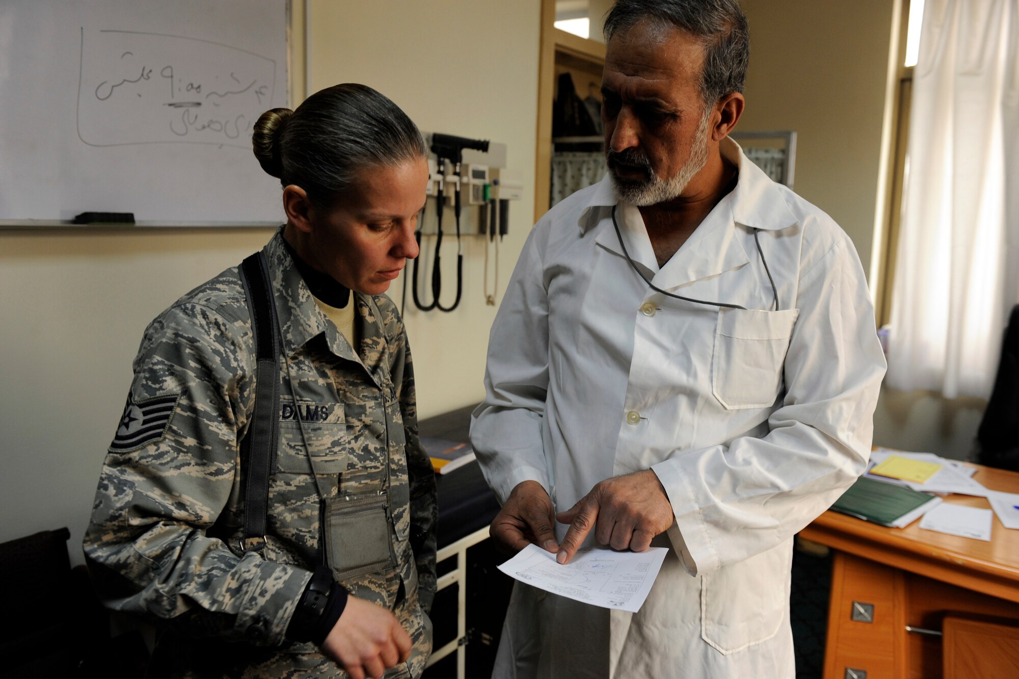 Tech. Sgt. Misti Adams, 438th Air Expeditionary Advisory Squadron medical advisor, and Afghan National Army Air Corps Col. Toryalay Sh-quraishee, Command Air Corps Medical Service Clinic commander, discuss a patient's lab results in the CACMSC Feb. 23, 2010, at Kabul International Airport, Afghanistan. Since the 438th AEAS medical advisors' arrival in May 2009, improvements in the clinic include better accountability of medical records, a pharmacy, a preventive medicine program (the equivalent of public health for U.S. forces) and sick call. The clinic?s most recent milestone was achieved Feb. 15, when six Afghan medics became the country?s first flight surgeons after graduating from a 9-month course here. (U.S. Air Force photo/Staff Sgt. Manuel J. Martinez/released)
