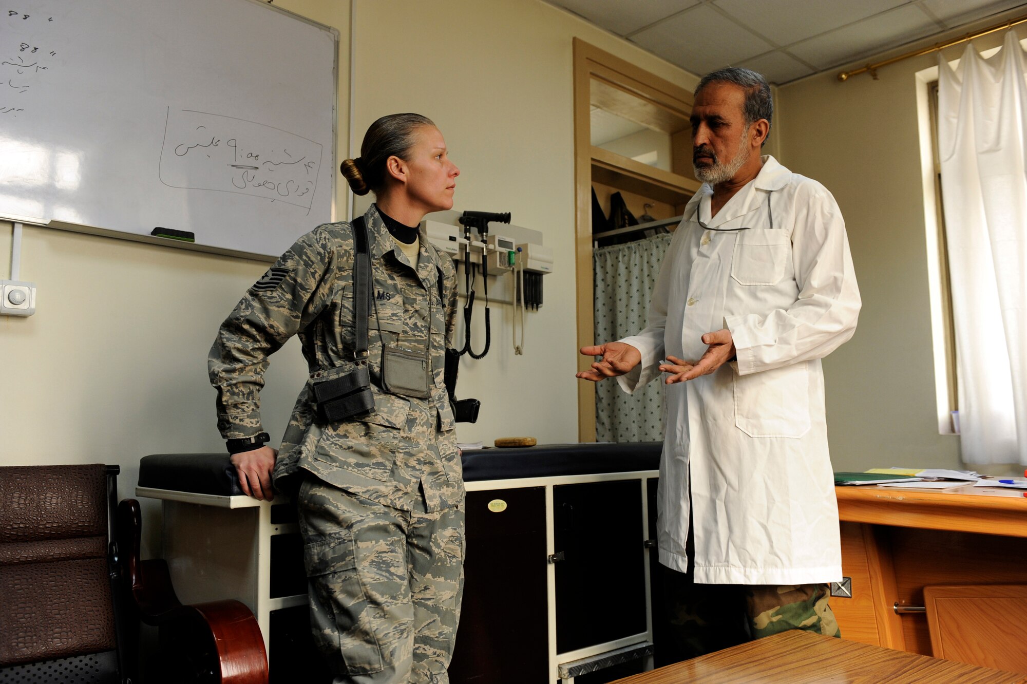 Tech. Sgt. Misti Adams, 438th Air Expeditionary Advisor Squadron medical advisor, and Col. Toryalay Sh-quraishee, Command Air Corps Medical Service Clinic commander and flight surgeon,  discuss a patient's lab results Feb. 23, 2010, at Kabul International Airport, Afghanistan. Airmen assigned to the 438th Air Expeditionary Advisory Squadron teach Afghan soldiers the skills necessary to keep their soldiers on the battlefield. (U.S. Air Force photo/Staff Sgt. Manuel J. Martinez/released)
