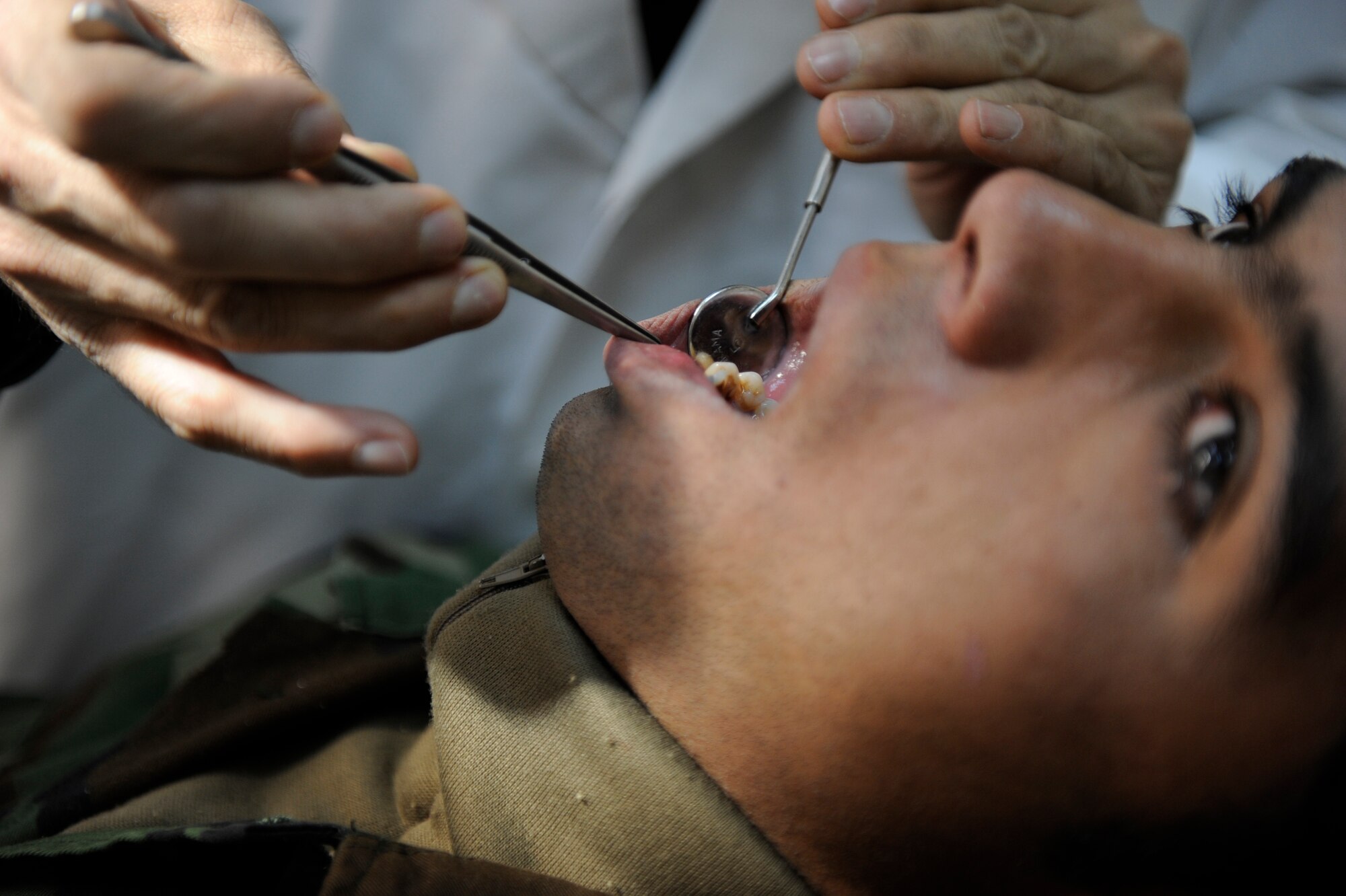 Major Azim Kazimy, Afghan National Army Air Corps (ANAAC) dentist, examines an ANAAC soldier's teeth at the ANAAC command Air Corps Medical Service facility Feb. 23, 2010, at Kabul International Airport, Afghanistan. (U.S. Air Force photo/Staff Sgt. Manuel J. Martinez/released)