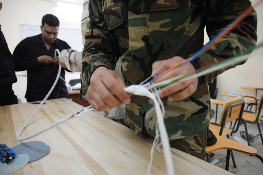 Iraqi military students from the 821st Expeditionary Training Squadron cable and antenna maintenance class unravel a long cable to separate what’s inside during class at Camp Taji, Iraq, Feb. 13, 2010.  During this 42 day course the Iraqi military students learn about theories, splicing cable and the overall capabilities that fiber optics can bring in advancements. (U.S. Air Force photo/Senior Airman Jarrod R. Chavana/Released)
