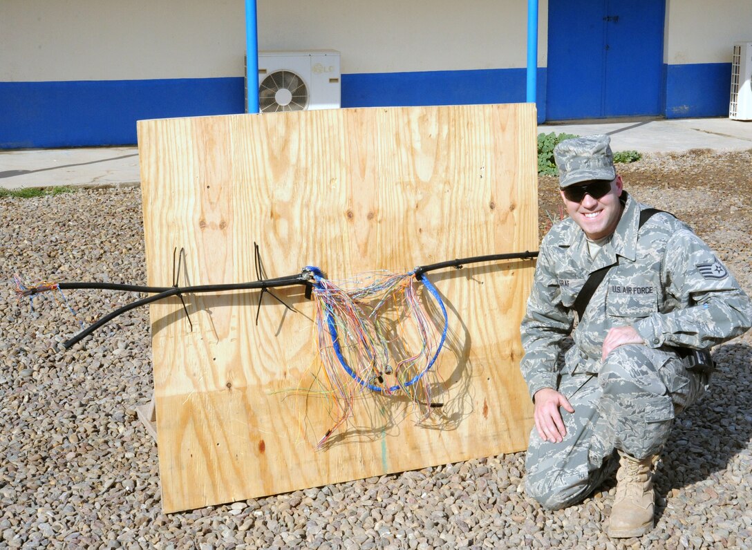Air Force Staff Sgt. Gary Graf, 821st Expeditionary Training Squadron cable and antenna maintenance instructor, sits next to a cable teaching aide he created for his class at Camp Taji, Iraq, Feb. 13, 2010. During this 42 day course the Iraqi military students learn about theories, splicing cable and the overall capabilities that fiber optics can bring in advancements. (U.S. Air Force photo/Master Sgt. Trish Bunting/Released)