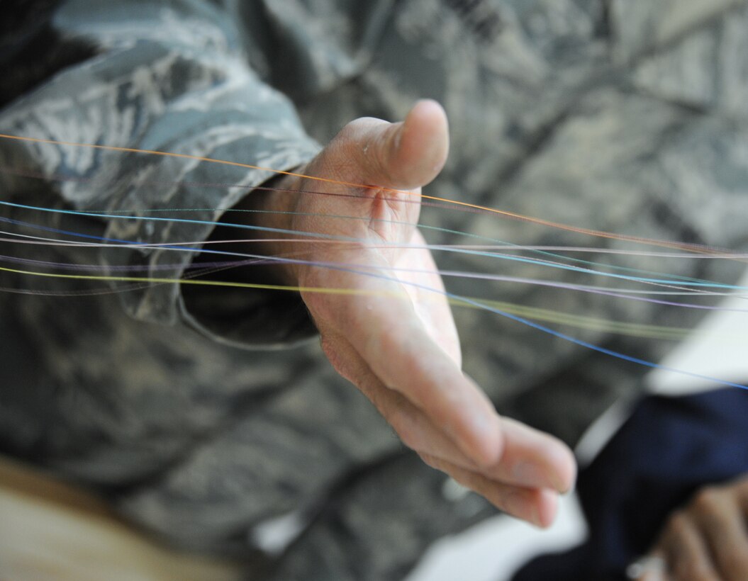 Air Force Staff Sgt. Gary Graf, 821st Expeditionary Training Squadron cable and antenna maintenance instructor, holds the separate colors of the different fiber optic wires during class at Camp Taji, Iraq, Feb. 13, 2010. During this 42 day course the Iraqi military students learn about theories, splicing cable and the overall capabilities that fiber optics can bring in advancements. (U.S. Air Force photo/Master Sgt. Trish Bunting/Released)