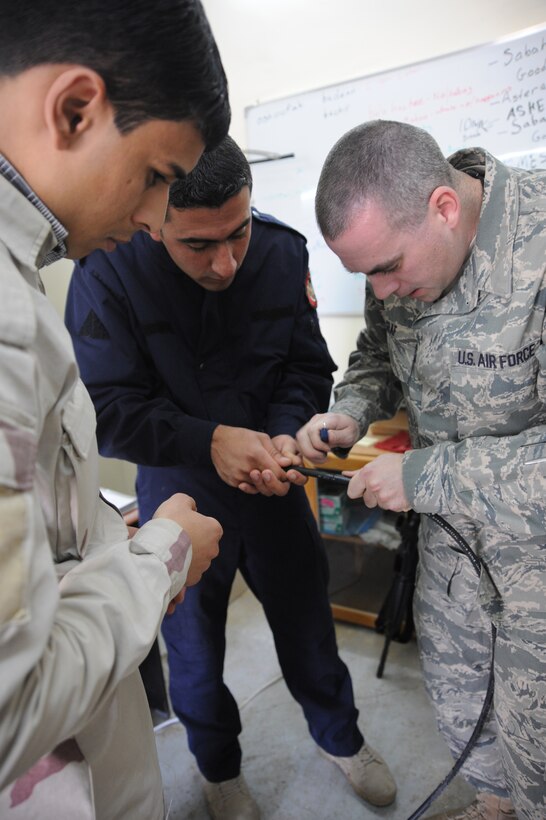 Air Force Staff Sgt. Gary Graf, 821st Expeditionary Training Squadron cable and antenna maintenance instructor, demonstrates to some of his students how to carefully cut open a cable and separate the different wires during class at Camp Taji, Iraq, Feb. 13, 2010. During this 42 day course the Iraqi military students learn about theories, splicing cable and the overall capabilities that fiber optics can bring in advancements. (U.S. Air Force photo/Master Sgt. Trish Bunting/Released)