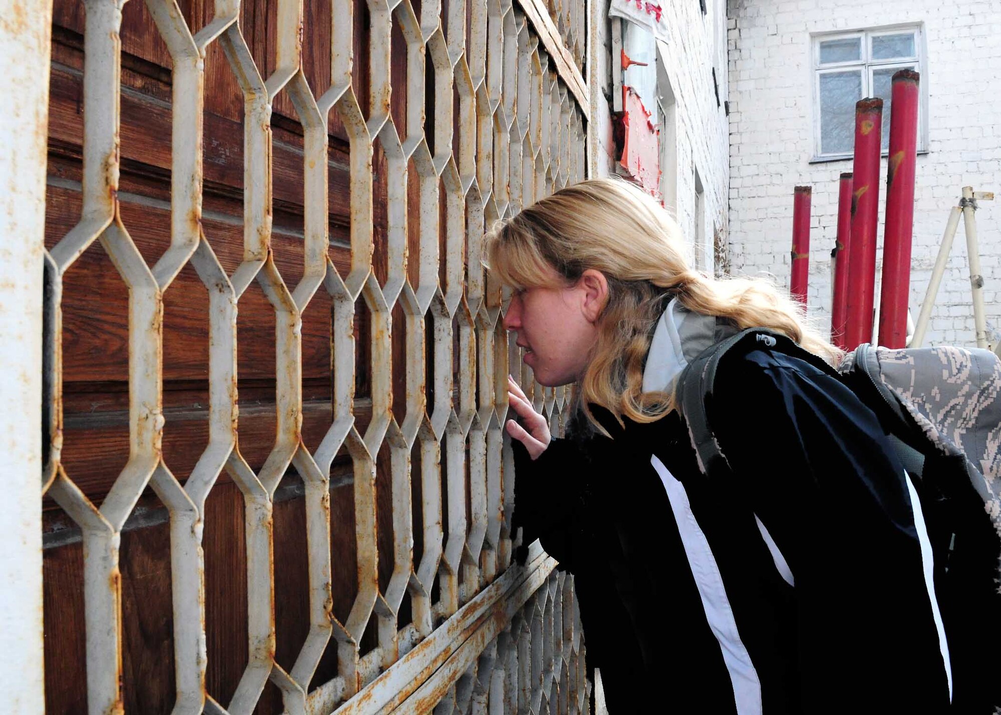 Master Sgt. Laurie Boros, 376th Air Expeditionary Wing client support administrator, peers inside the crack of the back door of a building that will soon be renovated to become the Crisis Center for Women in Bishkek, Kyrgyzstan, March 5. Transit Center at Manas Airmen, together with the Kyrgyz Congress of Women, will help make the crisis center a place women can come for refuge. There will be a ceremony soon to officially begin the renovations.  (U.S. Air Force photo/Staff Sgt. Carolyn Viss/released)