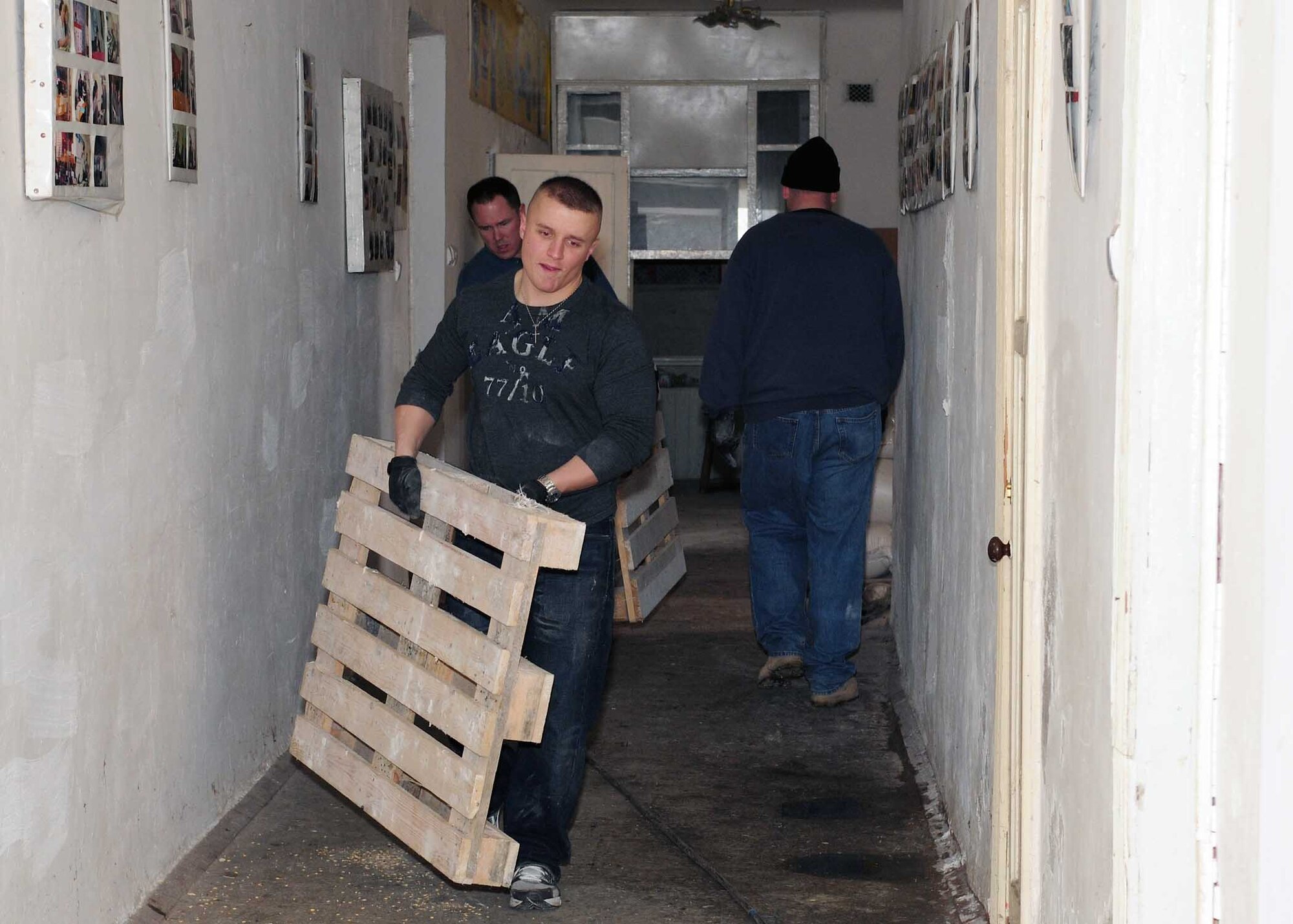 Senior Airman Wesley Kliwinski, 376th Expeditionary Force Support Squadron, and Lt. Col. Crag Cole, 376th Expeditionary Civil Engineer Squadron commander, carry wood pallets inside a building that will soon be renovated to become the Crisis Center for Women in Bishkek, Kyrgyzstan, March 5. Transit Center at Manas Airmen, together with the Kyrgyz Congress of Women, will help make the crisis center a place women can come for refuge. There will be a ceremony soon to officially begin the renovations. (U.S. Air Force photo/Staff Sgt. Carolyn Viss/released)