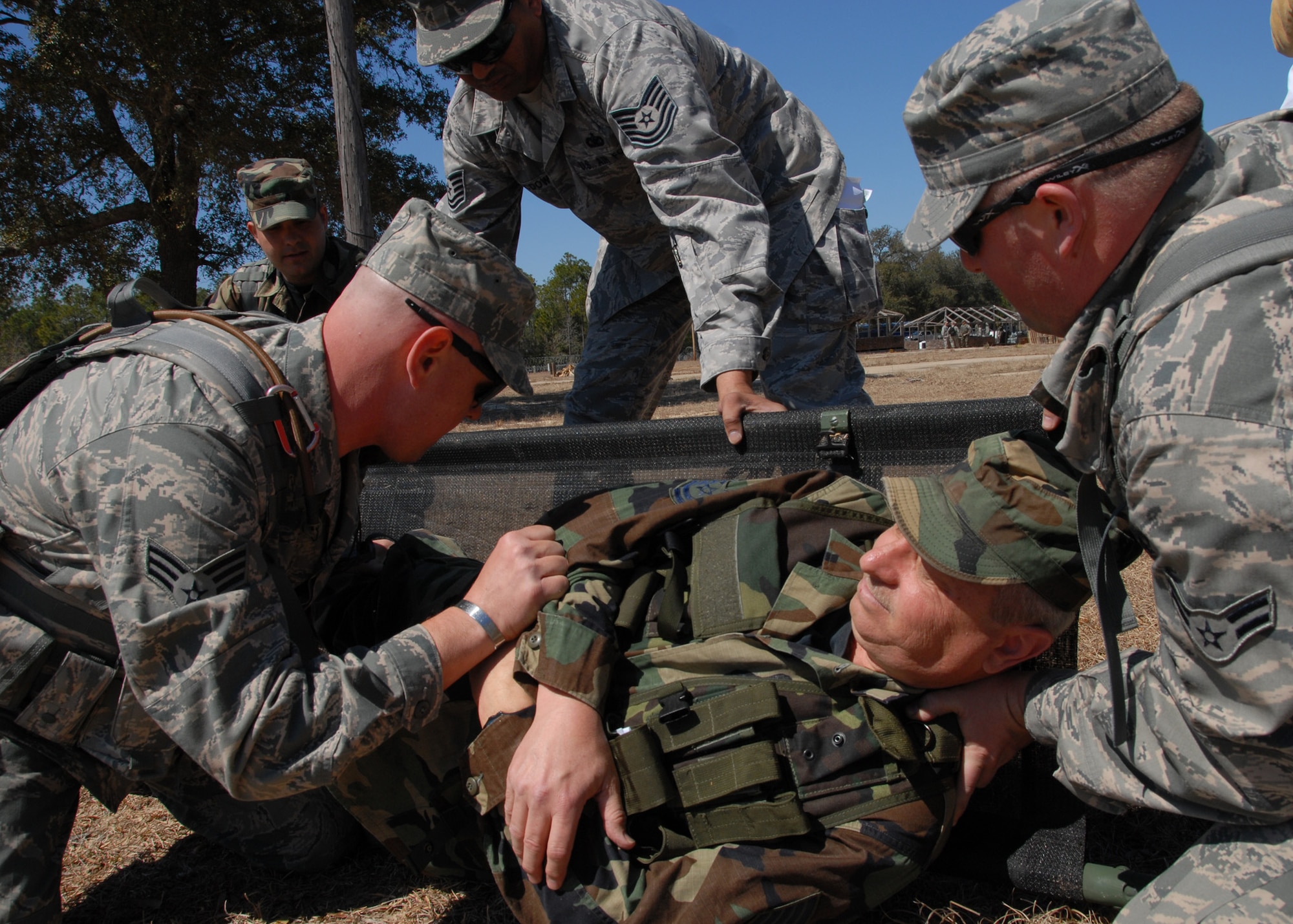 (Left to right) Senior Airman Don Brost and Airman 1st Class Chris Morie, 919th Security Forces Squadron, help Tech. Sgt. Hubert Homan onto a litter after setting his leg during the self-aid and buddy care scenario at Duke Field March 6.  The scenario was part of a Field Training Exercise for the 919th SFS during the UTA weekend.  Squads also participated in tent building, force-on-force movements, land navigation and prisoner search.  (U.S. Air Force photo/Tech. Sgt. Samuel King Jr.)