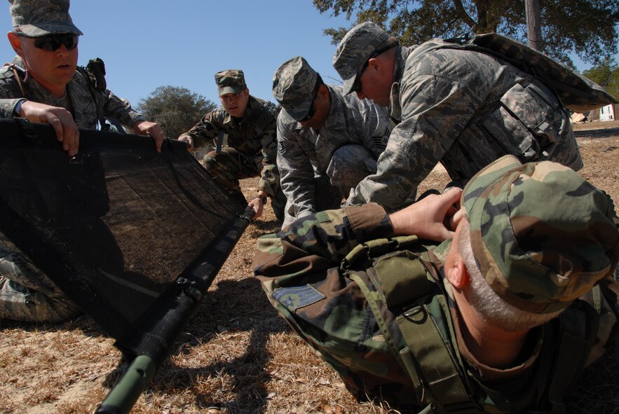 A litter is brought in by two Airmen, while others set the broken leg of a simulated victim during the self-aid and buddy care scenario at Duke Field March 6.  The scenario was part of a Field Training Exercise for the 919th Security Forces Squadron during the UTA weekend.  Squads also participated in tent building, force-on-force movements, land navigation and prisoner search.  (U.S. Air Force photo/Tech. Sgt. Samuel King Jr.)