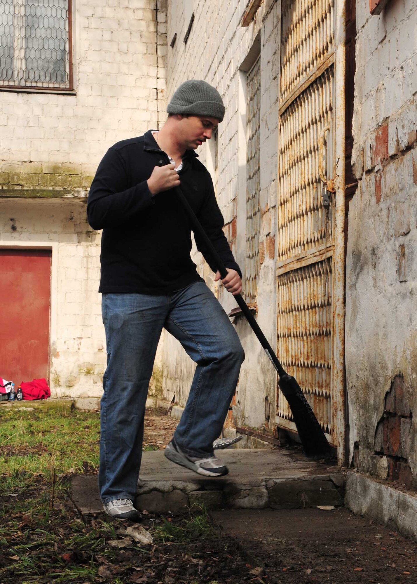 1st Lt. Nick Herr, 22nd Expeditionary Air Refueling Squadron, sweeps the back walkway of a building that will soon be renovated to become the Crisis Center for Women in Bishkek, Kyrgyzstan, March 5. Transit Center at Manas Airmen, together with the Kyrgyz Congress of Women, will help make the crisis center a place women can come for refuge. There will be a ceremony soon to officially begin the renovations.  (U.S. Air Force photo/Staff Sgt. Carolyn Viss/released)