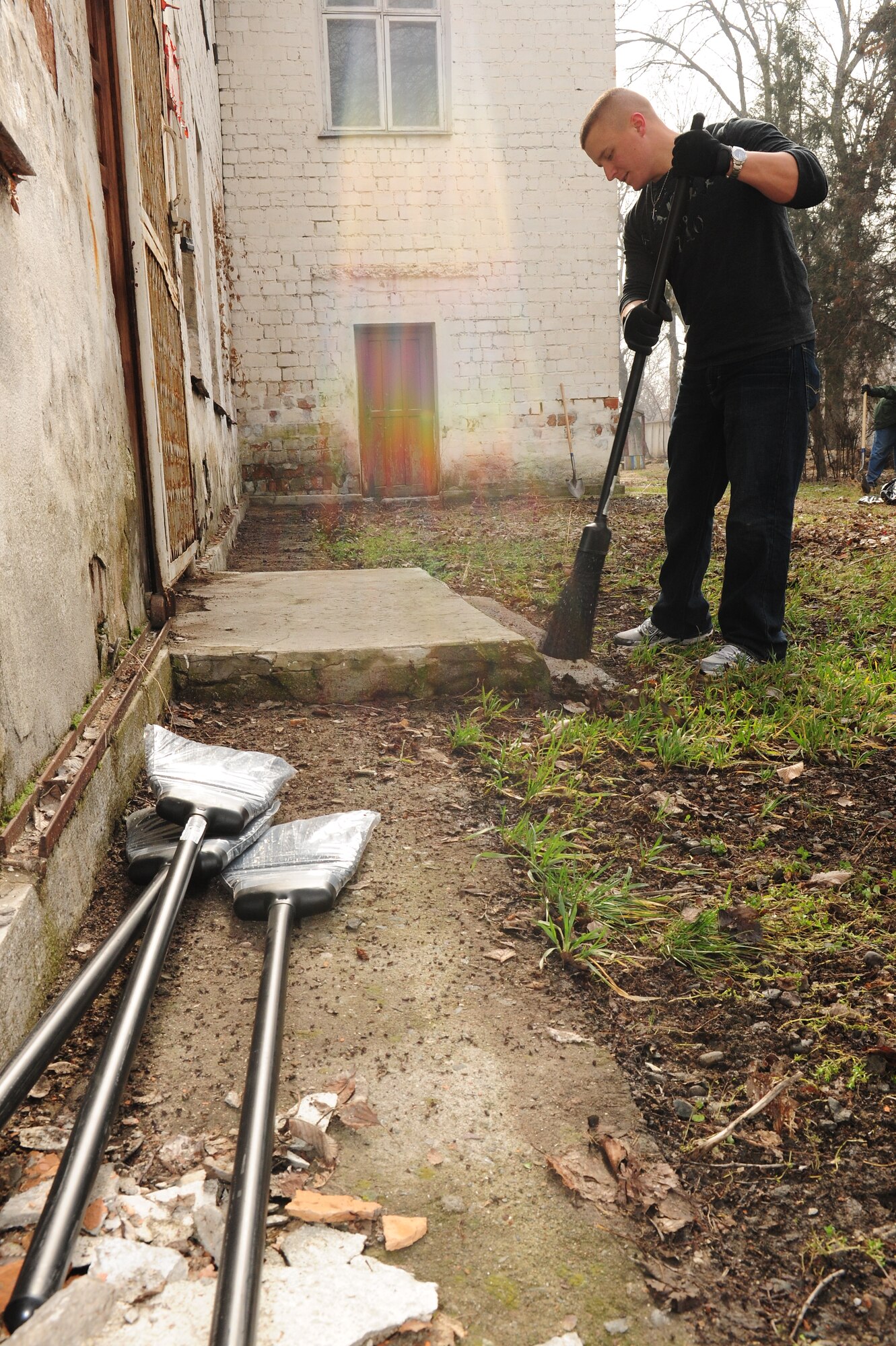 Senior Airman Wesley Kliwinski, 376th Expeditionary Force Support Squadron, sweeps the back walkway of a building that will soon be renovated to become the Crisis Center for Women in Bishkek, Kyrgyzstan, March 5. Transit Center at Manas Airmen, together with the Kyrgyz Congress of Women, will help make the crisis center a place women can come for refuge. There will be a ceremony soon to officially begin the renovations. (U.S. Air Force photo/Staff Sgt. Carolyn Viss/released)