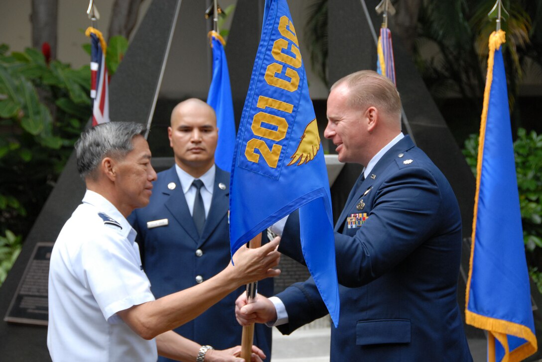 Major Gen. Darryl Wong, HIANG Commander, hands the unit the unit 'colors' over to Lt. Col. Gregory Schrivner during the 201st's activation ceremony, Mar. 7. (U.S. Air Force photo, A1C Orlando Corpuz)