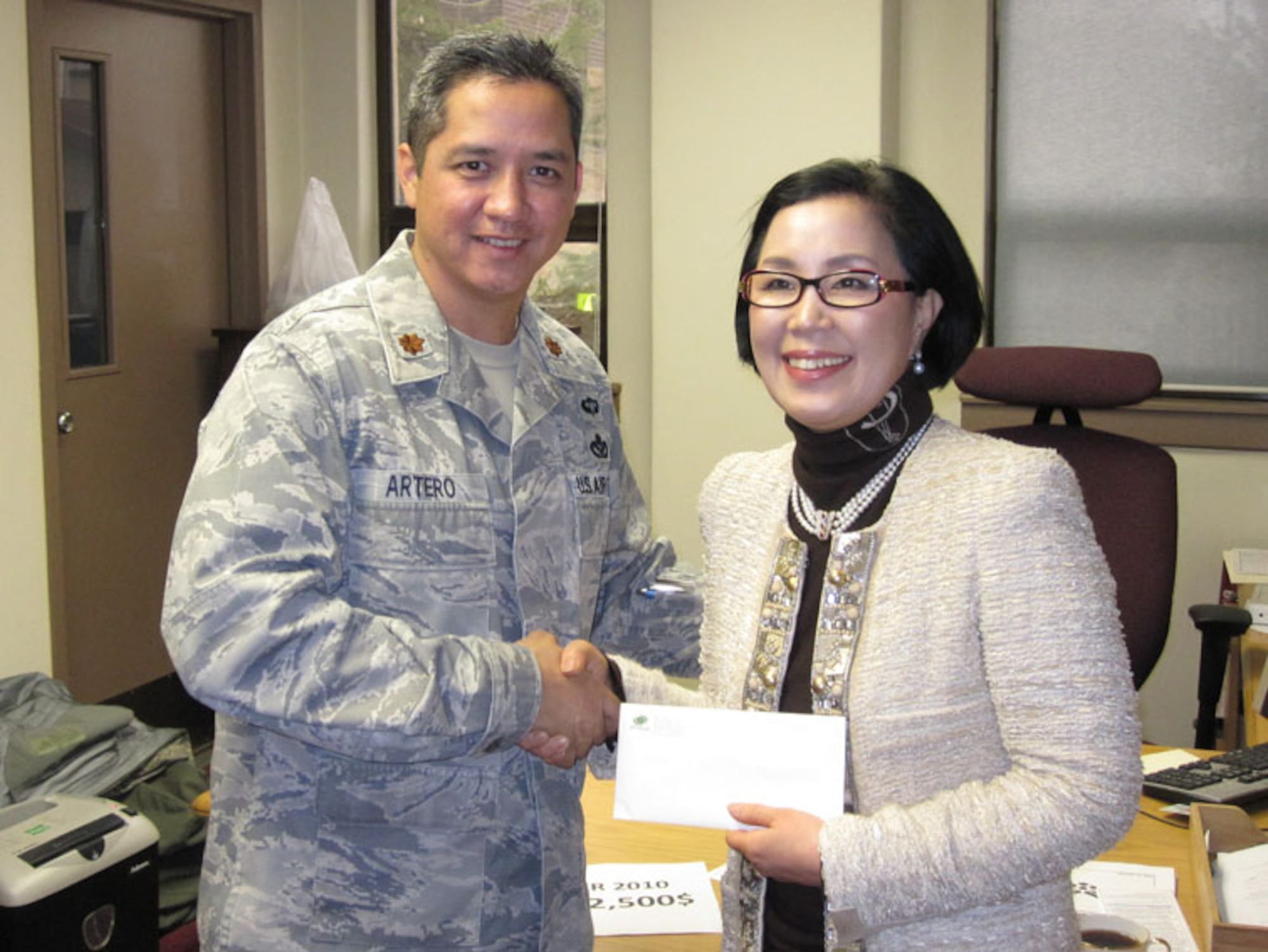 Maj. Audie Artero, Rush Park mayor, accepts a donation from Ms. Song, Sung Hee on behalf of nine members of the Korea America Good Neighbors Society Thursday. The donation will help provide food and entertainment for a barbecue to be held March 18 in appreciation of the augmentees from around the world who provided support for Key Resolve/Foal Eagle 10. (Courtesy photo)