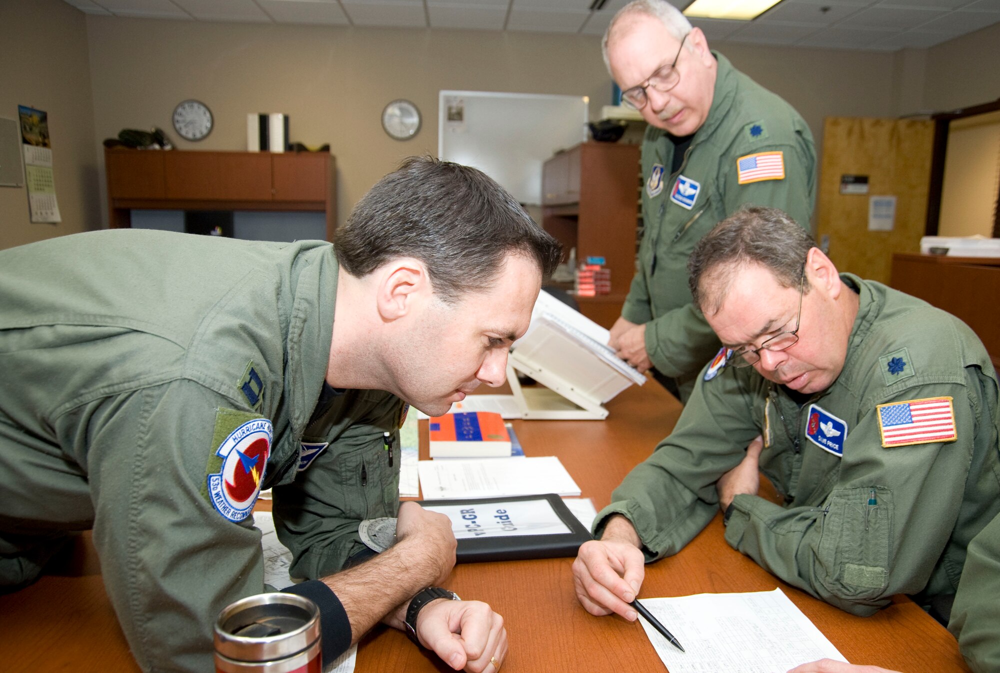 Captain Kelly Soich (left), 53rd Weather Reconnaissance Squadron navigator, reviews fuel consumption data with Lt. Col. Malcolm Shannon (standing) and Lt. Col. David Price, 53rd WRS navigators. This is one aspect of mission planning the navigators undertake before flying a storm mission with the Hurricane Hunters.