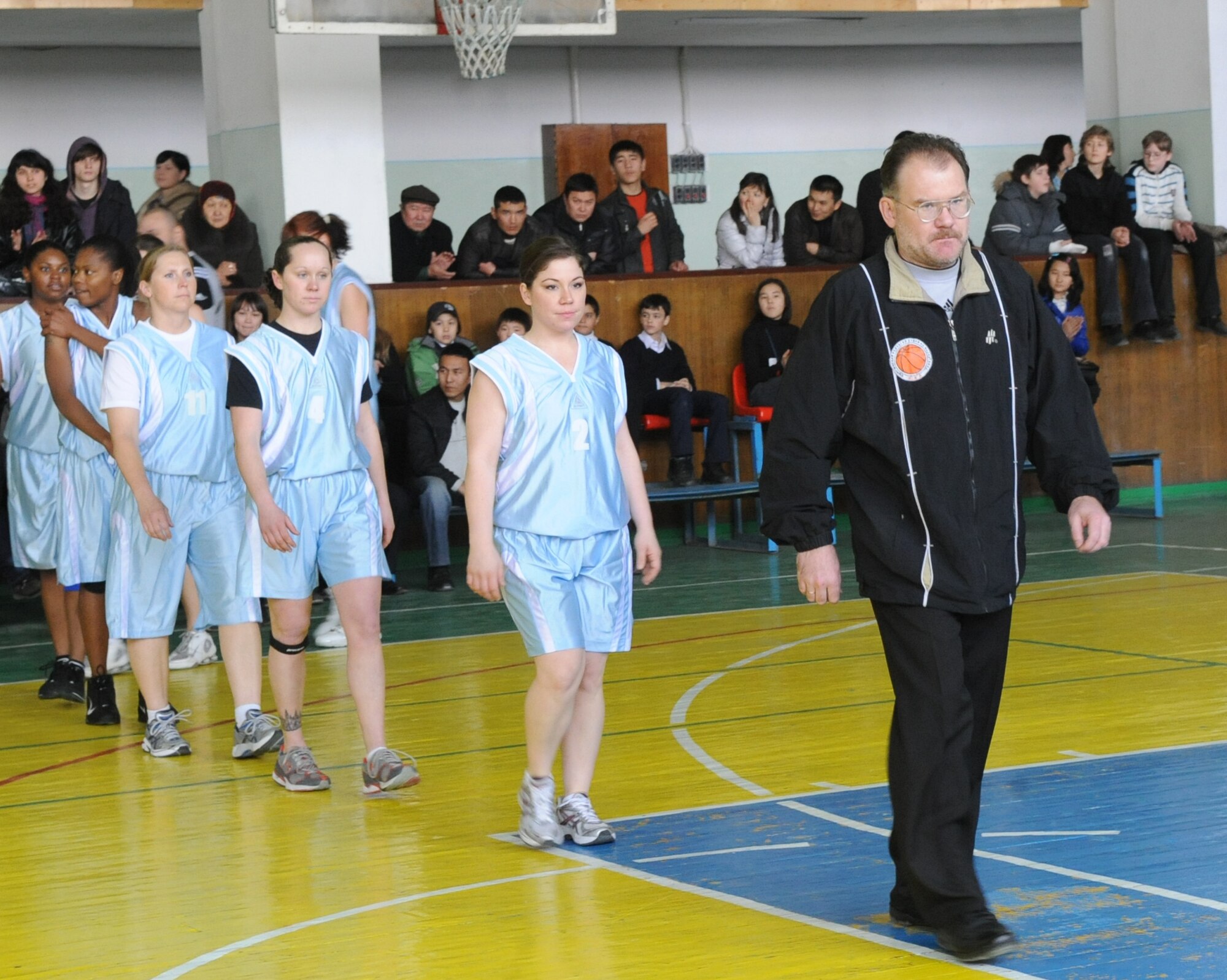 Seven women representing the Transit Center at Manas are escorted on to the court before playing a basketball game against Technical University at the Palace of Sport in Bishkek, Kyrgyzstan, March 5, 2010. The friendly game was played to honor International Women's Day, which is celebrated annually on March 8.  (U.S. Air Force photo/Senior Airman Nichelle Anderson/released)
