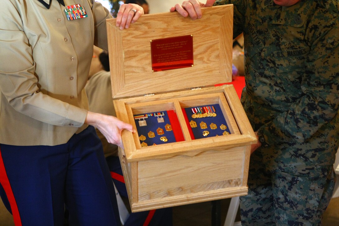 Col. Susan B. Seaman, commanding officer of Headquarters and Support Battalion, Marine Corps Base Camp Lejeune, and Sgt. Maj. Michael Wootten, HQSPTBN sergeant major, MCB Camp Lejeune, presents retired Master Gunnery Sgt. Marcia McLaurin, family readiness officer of HQSPTBN, MCB Camp Lejeune, after her retirement ceremony at the base stables, March 8.