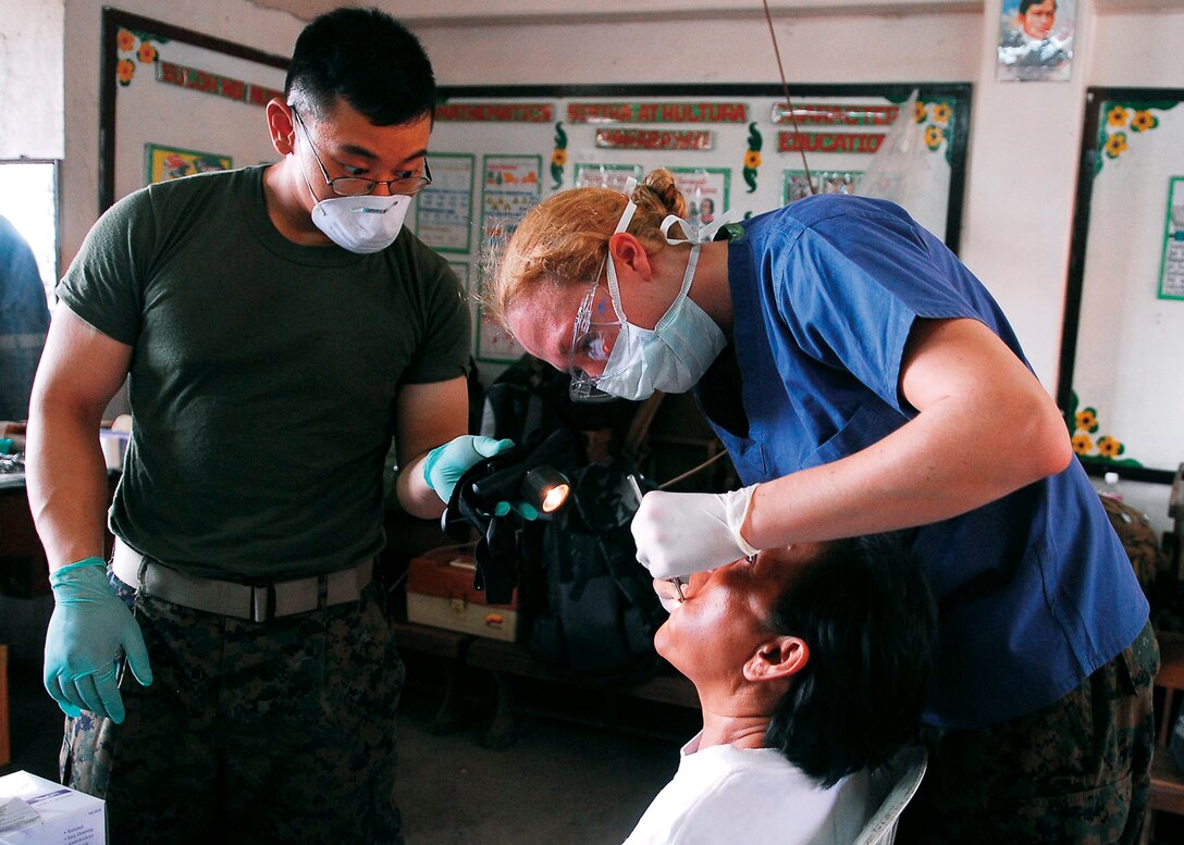 Seaman Daniel Ngo and Lt. Pamela Hartman, from Combat Logistics Battalion Health Service Support Team, 31st Marine Expeditionary Unit, remove a tooth from a Filipino patient during a medical civil action project at San Juan Elementary School March 8. The 31st MEU is operating with the forward-deployed Essex Amphibious Ready Group as part of Balikatan 2010, an annual bilateral exercise designed to improve interoperability between the United States and the Philippines.