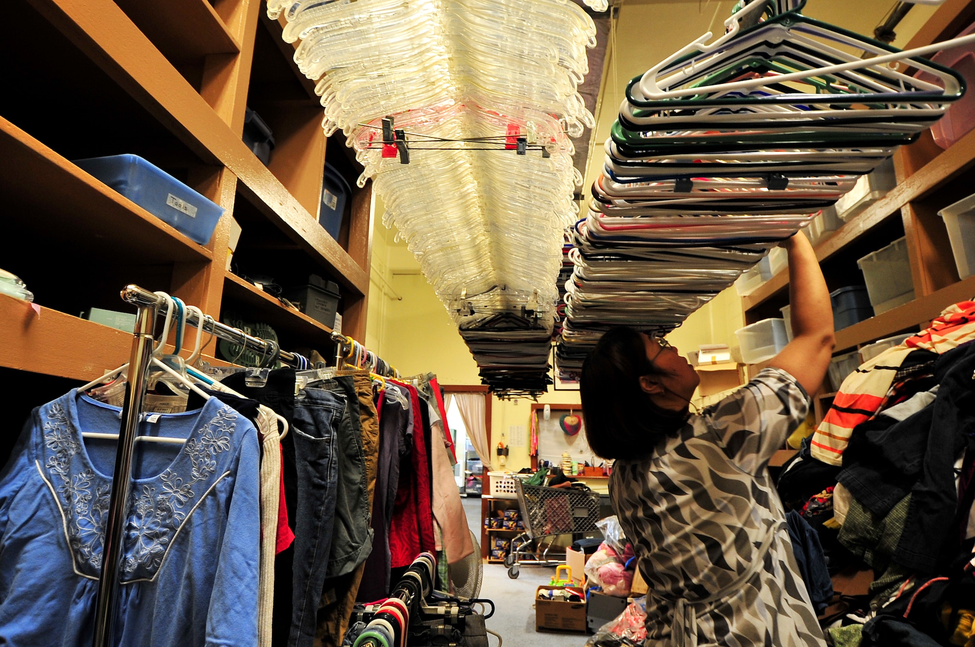 Maria Mangapit, thrift store employee, hangs a pile of clothes generously donated by servicemembers at the Okinawa Enlisted Spouses Club Thrift Store and Uncle Sam's Attic Feb. 26. OESC and USA is a non-profit organization which supports American and Japanese charitable projects and special interest groups on Okinawa. Some of their contributions in 2009 was supplying $8K worth of uniforms, boots and accessories to military members island wide; $66K to the Okinawa Enlisted Spouse Club; and 89K in toys, clothes and shoes for distribution to needy families all over the world. "The thrift store saves a lot of money for Airmen and their families to have things they couldn't afford," said Brig. Gen. Ken Wilsbach."The service provided for the Airmen is greatly appreciated."  The thrift store is asking for volunteers to help continue the success of the group and its mission.(U.S. Air Force photo/Tech. Sgt. Rey Ramon)                      