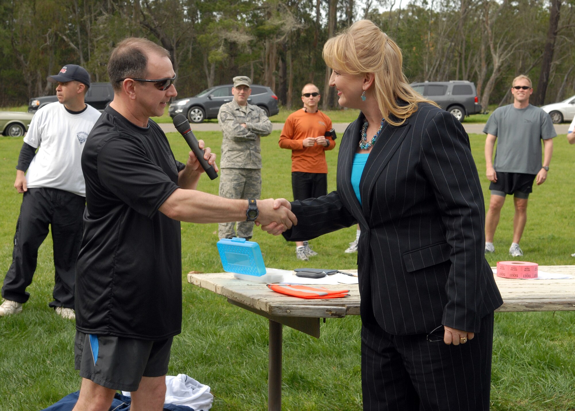 VANDENBERG AIR FORCE BASE, Calif. - - Before the start of the Guardian Challenge 5K Run, Col. Steven Winters, the 30th Space Wing vice commander, presents a coin to Debbie Hargreaves of the Space Missile Systems Detachment 2 here Friday, March 5, 2010. Mrs. Hargreaves designed the new costume for Hawkman who attended the Guardian Challenge run. (U.S. Air Force photo/Airman 1st Class Angelina Drake)