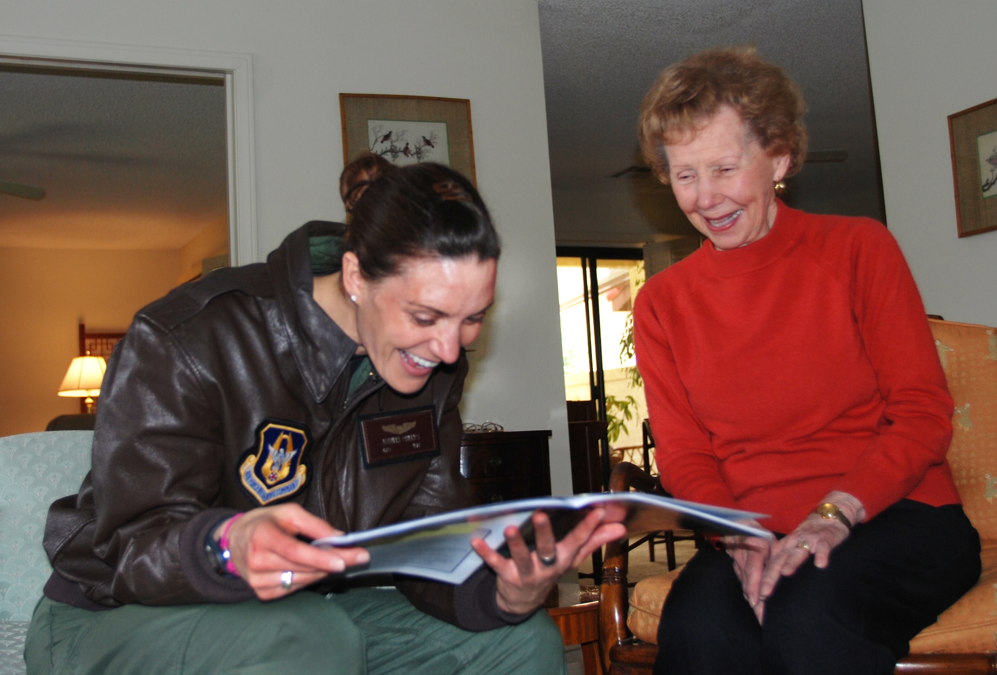 Women's Airforce Service Pilot, Mrs. Margo deMoss (right) shows Capt. Jennifer Phillips candid photos in a WASP reunion program.  Captain Phillips, who is a KC-135 pilot with the 336th Air Refueling Squadron at March Air Reserve Base, Calif., visited de Moss at her home near the base, March 5, 2010.  (U.S. Air Force photo/Megan Just)