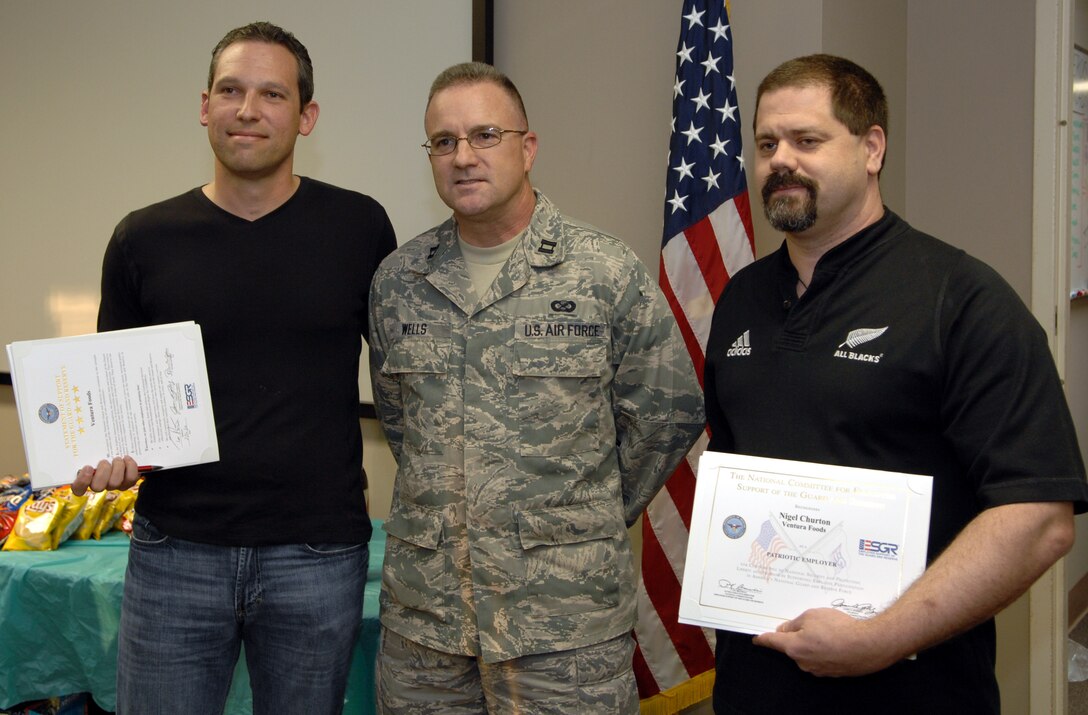 U.S. Air Force Reserve Captain Evert Wells, Officer in Charge for the deploying 4th Combat Camera Squadron team, March Air Reserve Base, Calif., stands between his civilian employment manager Tom Rochester (L), and his civilian employment supervisor Nigel Churton, from Ventura Foods, Ventura, Calif.  The employers hold their Patriot Award certificates of appreciations at a barbeque celebration for the deploying team at the 4th Combat Camera Squadron, March Air Reserve Base, Calif., Feb. 20, 2010. (U.S. Air Force Photo/Staff Sgt. Stephen Schester)(Released)