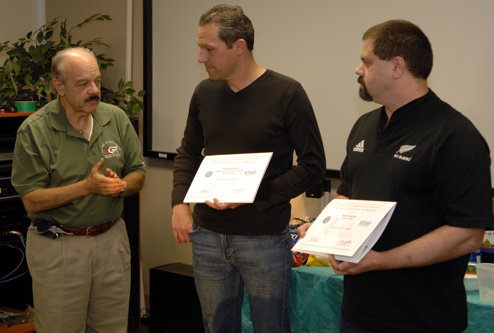 Retired Air Force Reserve Colonel John Columbine (L), Employer Support for the Guard and Reserve representative, presents Patriot Award certificates of appreciation to Tom Rochester and Nigel Churton, civilian manager and supervisor to Captain Evert Wells, Officer in Charge for the deploying 4th Combat Camera Squadron team, March Air Reserve Base, Calif., during a squadron barbeque Feb. 20, 2010. (U.S. Air Force photo/Staff Sgt. Stephen Schester)(Released)