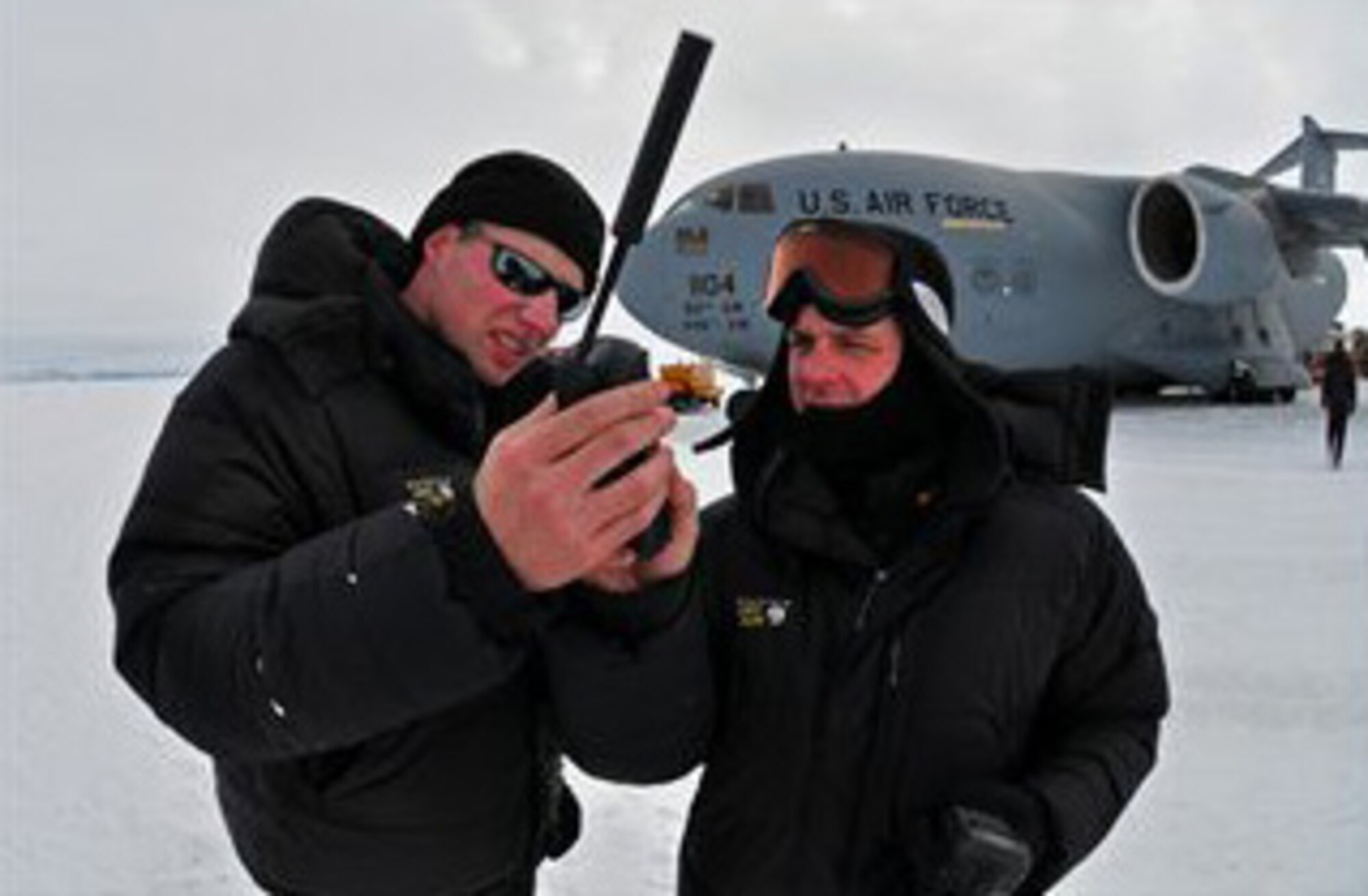 PEGASUS FIELD, Antarctica- Capt. Rob Selmer, 97th Airlift Squadron, and Tech. Sgt. Quentin Nemechek, 446th Aircraft Maintenance Squadron, both Reservists out of Joint Base Lewis-McChord, Wash., review satellite iridium phone operations here, during an Operation Deep Freeze mission. (U.S. Air Force photo/Staff Sgt. Robert Tingle)