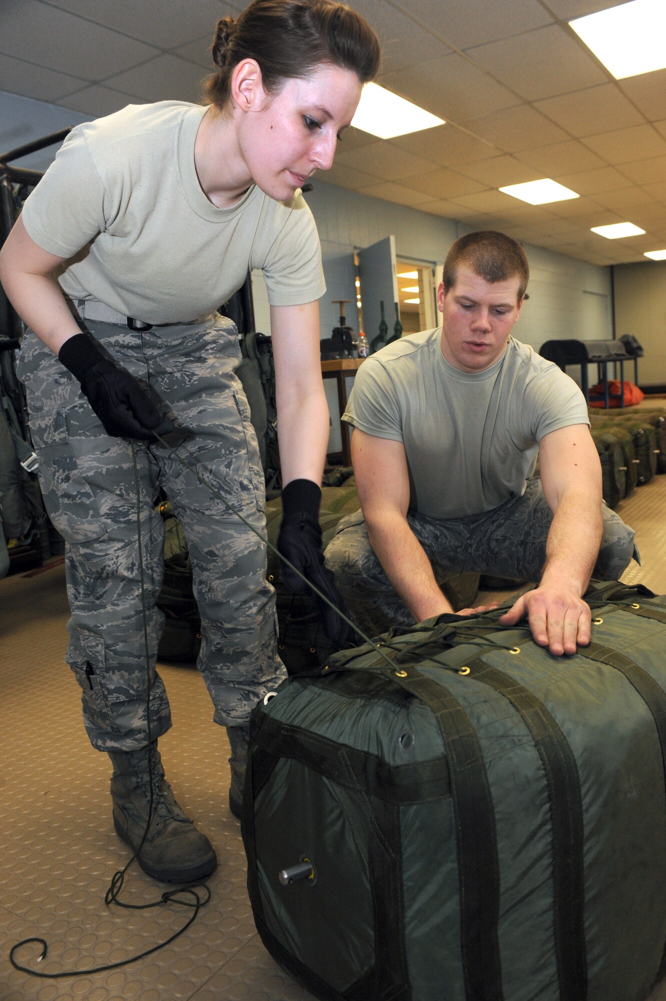 MINOT AIR FORCE BASE, N.D. – Senior Airman Cody Lytle (right), 5th Operations Support Squadron aircrew flight equipment technician, assist Airman 1st Class Christian Krueger, 5th Operations Support Squadron aircrew flight equipment apprentice, compress B-52H Stratofortress drag chute survival kits at the AFE parachute shop Mar. 4. Aircrew flight equipment members inspect and maintain life-saving appliances and gear for the B-52H aircraft as well as all 5th Bomb Wing aircrew personnel. (U.S. Air Force photo by Senior Airman Jesse Lopez)