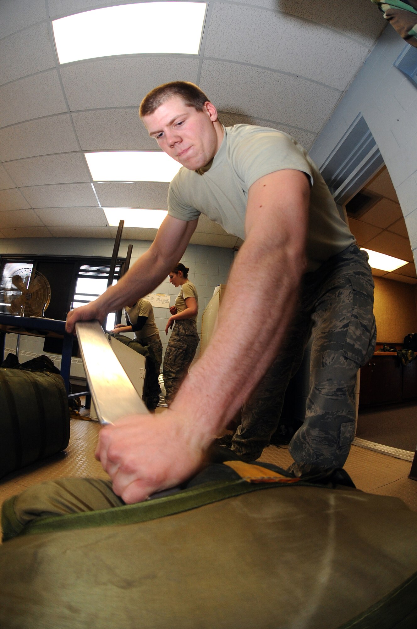 MINOT AIR FORCE BASE, N.D. – Senior Airman Cody Lytle, 5th Operations Support Squadron aircrew flight equipment technician, uses a metal rod to pack a B-52H Stratofortress drag chute survival kit at the AFE parachute shop Mar. 4. Aircrew flight equipment members inspect and maintain life-saving appliances and gear for the B-52H aircraft as well as all 5th Bomb Wing aircrew personnel. (U.S. Air Force photo by Senior Airman Jesse Lopez)