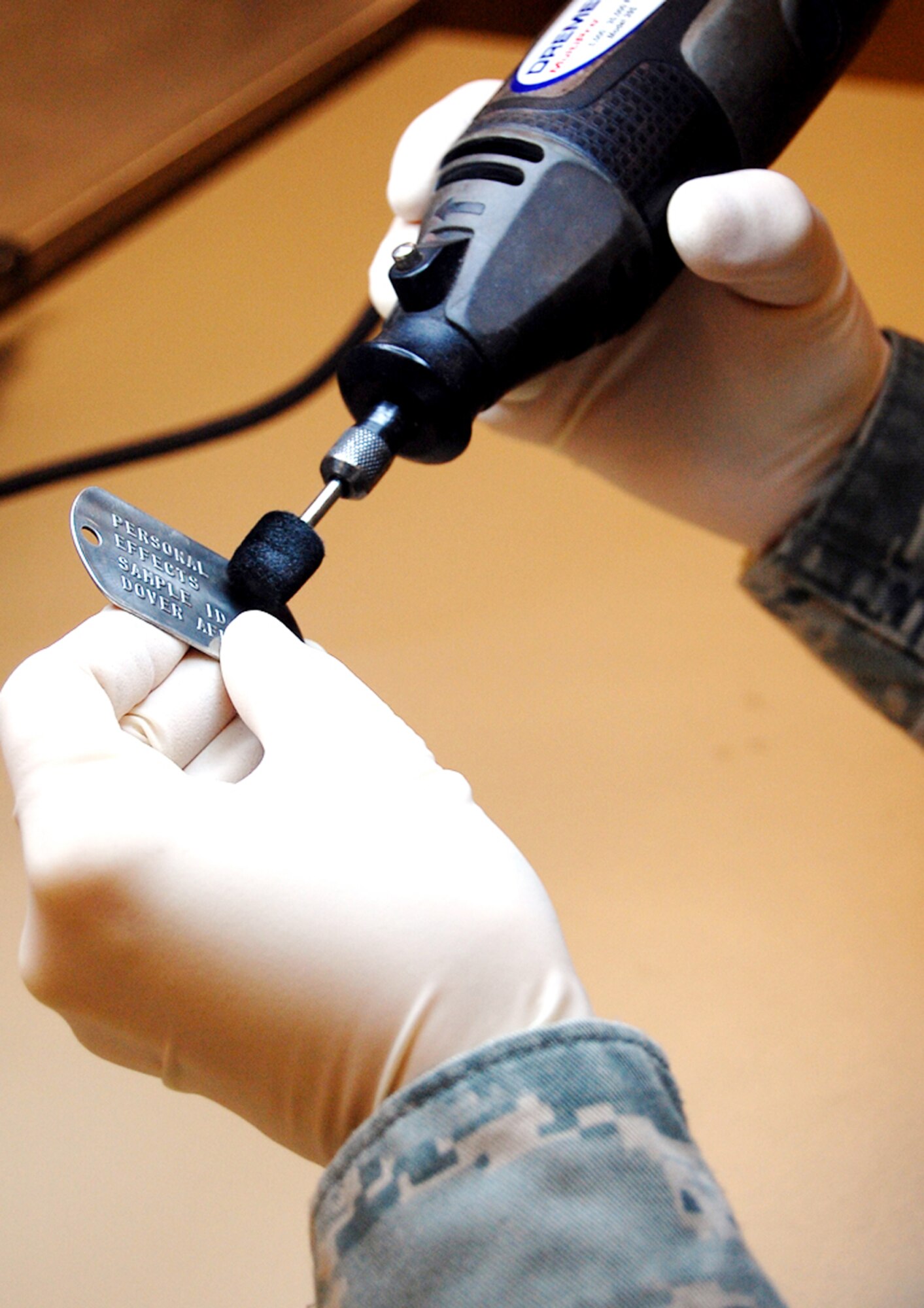 Master Sgt. Tracy Bailey cleans a dog tag at the personal effects section of the Air Force Mortuary Affairs Operations Center Feb. 25, 2010, at Dover Air Force Base, Del. (U.S. Air Force photo)