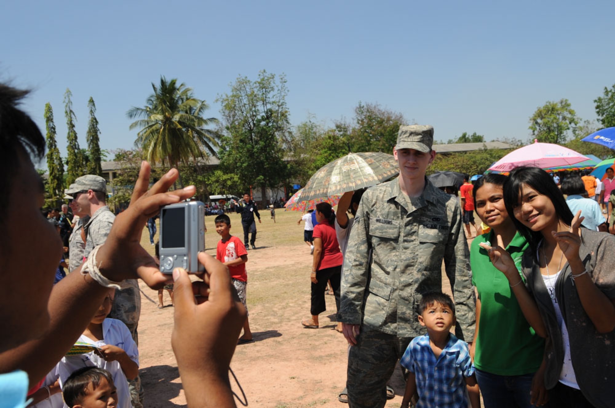 Airman 1st Class Cass Williams, a native of Arcadia, Fla., and a member of the 19th Aircraft Maintenance Squadron at Elmendorf Air Force Base, Alaska, poses for pictures with local Thai residents while at the Ban Nong Sroung School in Ban Nong Sroung, Thailand, March 4. U.S., Thai and Singaporean airmen joined together to provide medical, dental and optometry care to local Thai residents as part of Cope Tiger 2010.  The airmen also donated money, school supplies, toys and games to Ban Nong Sroung school children.  Cope Tiger, conducted this year March 1 to 12 from both Korat and Udon Thani Royal Thai Air Force Bases in Thailand, is a multilateral aerial large force exercise aimed at improving interoperability and strengthening relationships with partner nations in the Asia-Pacific region. (U.S. Air Force photo/Tech Sgt. Cohen A. Young)