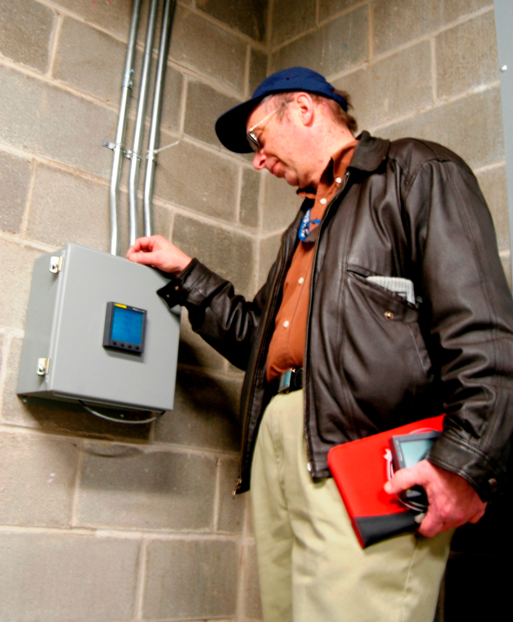 Base Energy Manger, Mr. Gavin Jones, reads an electrical meter on how much energy is being used by one of the base dormitories to compile a facility electrical signature.  Such readings can help trace phantom loads, which if eliminated, can save the base on electrical cost. (U.S. Air Force photo by Ted Theopolos)