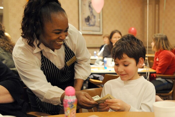 Velva Morton gives Chase Witmore the cash winnings for his bingo during Family Night at the Charleston Club March 4, 2010, at Joint Base Charleston, S.C. Families enjoyed pizza, spaghetti, ice cream and bingo at this month's event. The next scheduled Family Night is set for April 1, 2010. Ms. Morton is a staff member with the Charleston Club and Chase is the son of Jake and Heather Witmore who were guests of a JB CHS member for the night. (U.S. Air Force photo/Staff Sgt. Marie Brown)