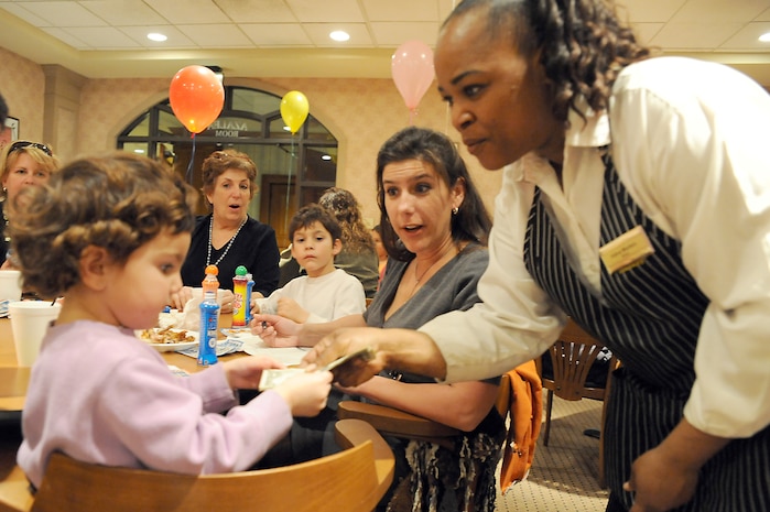 Velva Morton gives Olivia Witmore the cash winnings for her bingo during Family Night at the Charleston Club March 4, 2010, at Joint Base Charleston, S.C. Families enjoyed pizza, spaghetti, ice cream and bingo at this month's event. The next scheduled Family Night is set for April 1, 2010. Ms. Morton is a staff member with the Charleston Club, and Olivia is the daughter of Jake and Heather Witmore who were guests of a JB CHS member for the evening. (U.S. Air Force photo/Staff Sgt. Marie Brown)