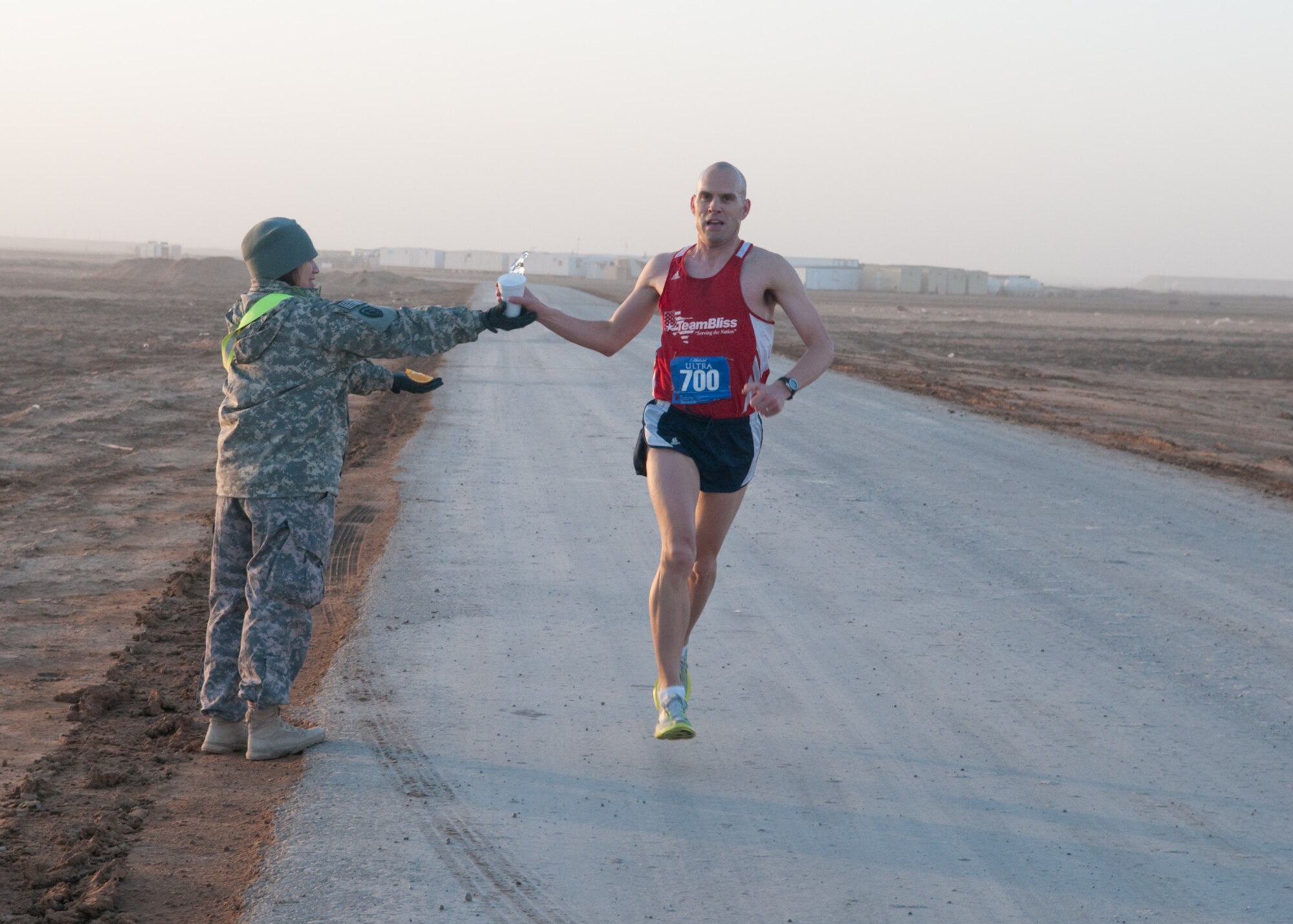 U.S. Army Sgt. Derek Miller, 4th Brigade Combat Team 1st Armor Division from Fort Bliss Texas, the sponsor of the El Paso Half-Marathon grabs a drink of water at mile-marker nine drink and aid station during the 13.1 mile course around Contingency Operating Base Adder, Iraq, Feb. 26, 2010. Sgt. Miller won first place with a run time of 1 hour 17 minutes. Over 450 servicemembers and civilians participated in the marathon. (U.S. Air Force photo by Senior Master Sgt. Elizabeth Gilbert/released)