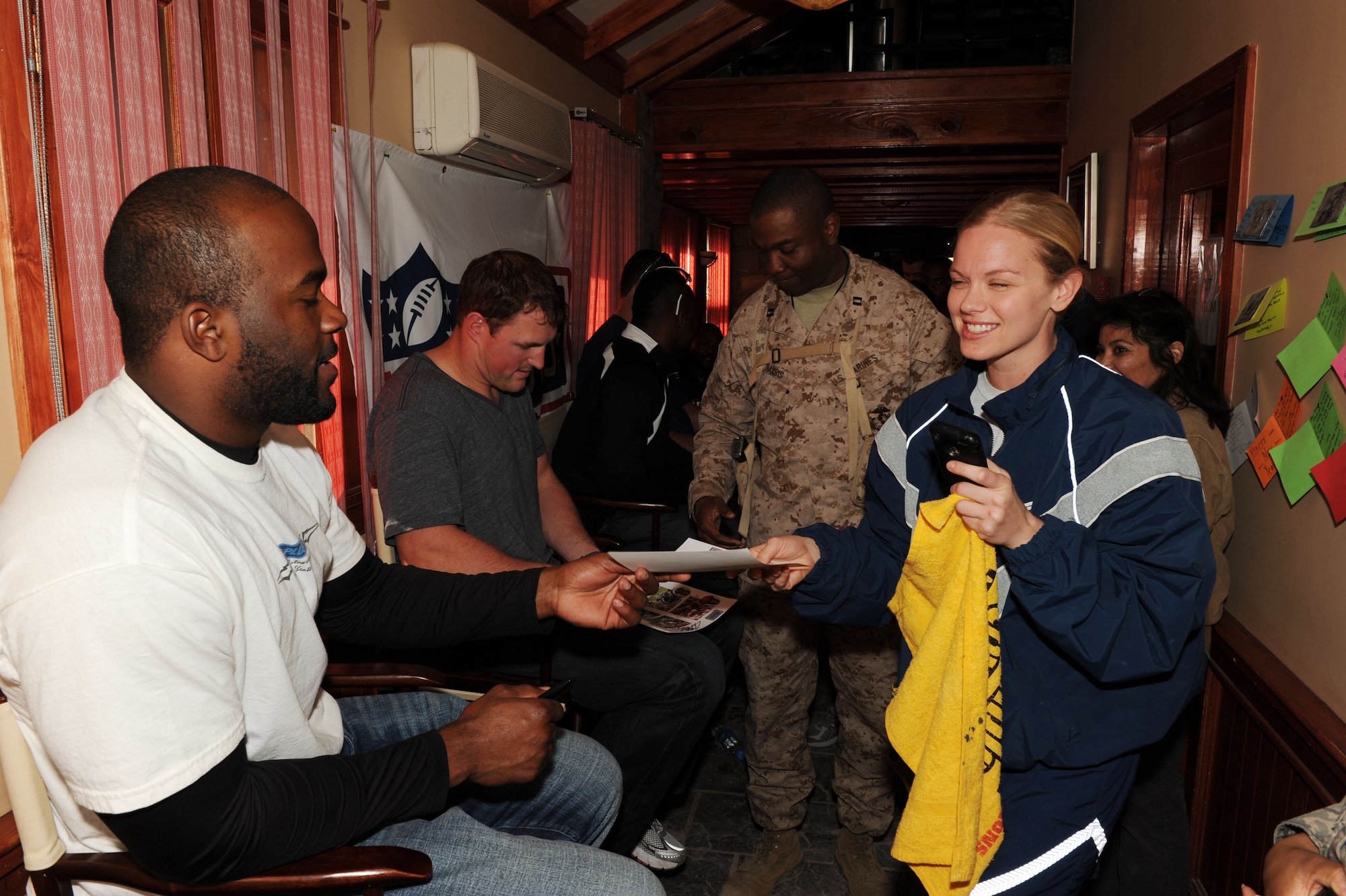Mario Williams of the Houston Texans hands an autograph to Tech. Sgt. Kimberly Price, 455th Aeromedical Evacuation Squadron, during an autograph session at the Pat Tillman USO on Bagram Airfield, March 5, 2010. The National Football League players are on a USO-sponsored tour of the U.S. Central Command area of operations. (U.S. Air Force photo/Staff Sgt. Richard Williams)
