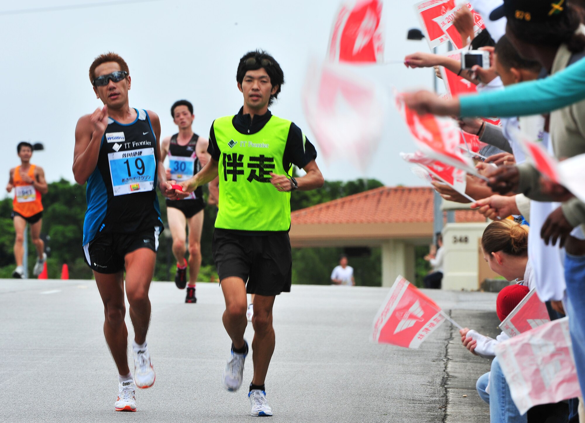 Americans and Okinawans participating in the Okinawa Marathon receive cheers from volunteers March 7 at Kadena Air Base, Japan. Team Kadena volunteers encouraged and provided water to runners as they participated in the Kadena portion of the marathon. The marathon runs through nine different cities,towns,and villages in central Okinawa at a distance of 26.4 miles. The marathon aims to encourage people to enjoy running and increase their fitness level throughout Okinawa.  (U.S. Air Force photo/Tech. Sgt. Rey Ramon)         