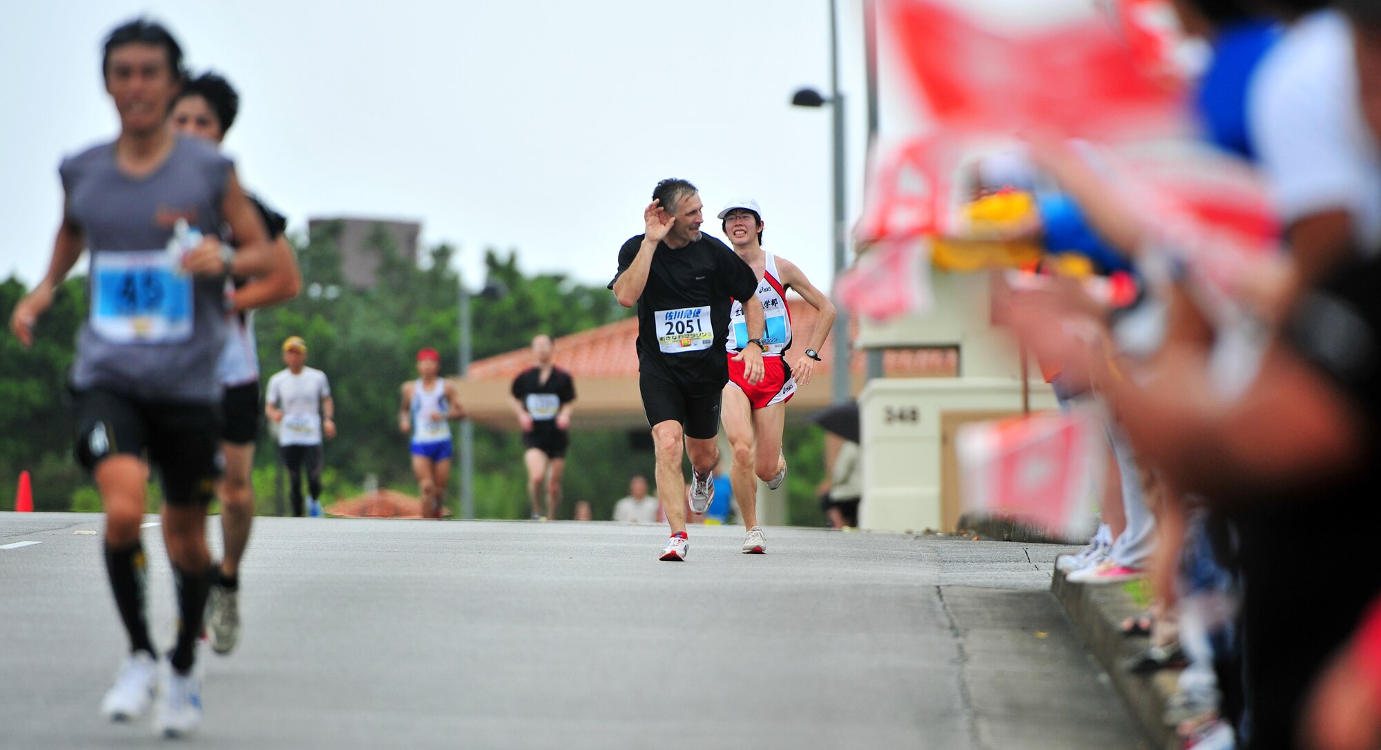 An American runner calls for louder cheers from the crowd March 7 at Kadena Air Base, Japan. Team Kadena volunteers encouraged and provided water to runners as they participated in the Kadena portion of the marathon. The marathon runs through nine different cities,towns,and villages in central Okinawa at a distance of 26.4 miles. The marathon aims to encourage people to enjoy running and increase their fitness level throughout Okinawa.  (U.S. Air Force photo/Tech. Sgt. Rey Ramon)     