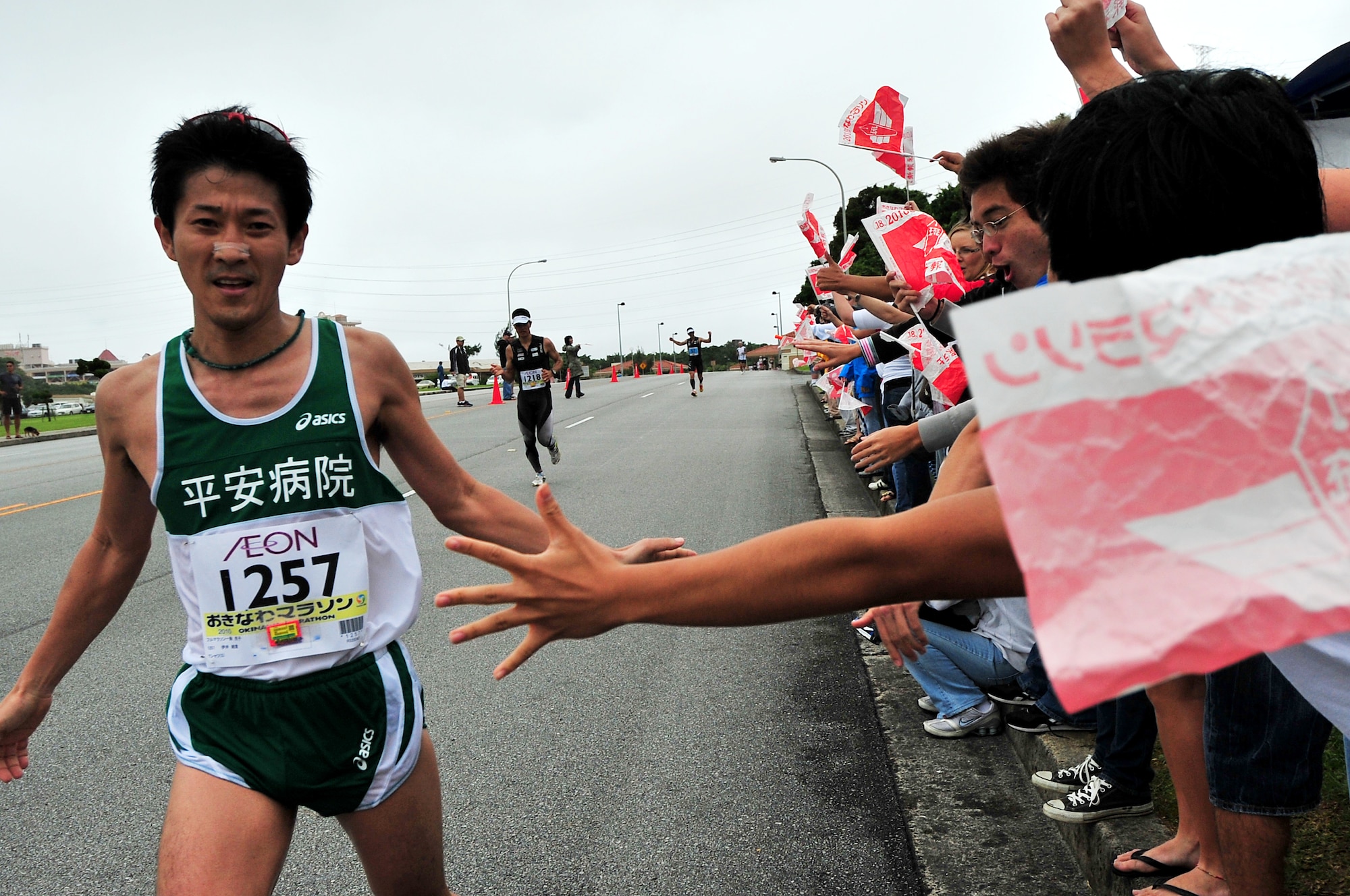 Volunteers cheer on American and Okinawan runners participating in the Okinawa Marathon March 7 at Kadena Air Base, Japan. Team Kadena volunteers encouraged and provided water to runners as they participated in the Kadena portion of the marathon. The marathon runs through nine different cities,towns,and villages in central Okinawa at a distance of 26.4 miles. The marathon aims to encourage people to enjoy running and increase their fitness level throughout Okinawa.  (U.S. Air Force photo/Tech. Sgt. Rey Ramon)        