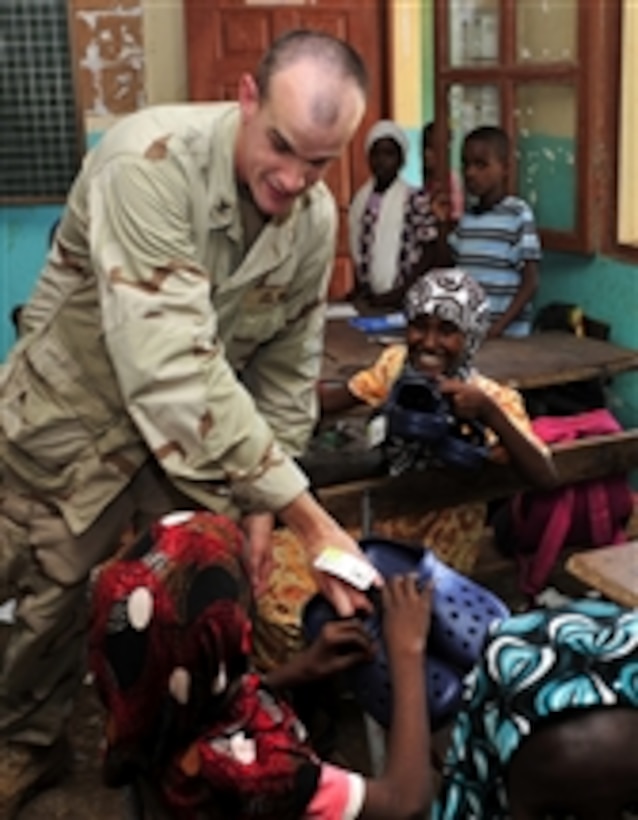 U.S. Navy Petty Officer 2nd Class Norman R. Otters hands out shoes to students at the Guelleh Batal School in Djibouti on March 1, 2010.  World Emergency Relief donated approximately 10,000 pairs of shoes to the chapel at Camp Lemonier, which distributed them to local schools, refugee camps, churches and Army Civil Affairs detachments.  