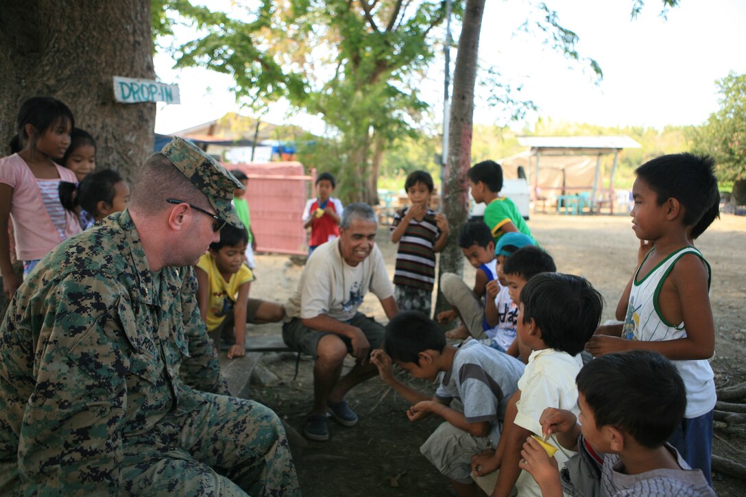 Maj. Peter Forsythe, executive officer for Combat Logistics Battalion 31 (CLB-31), 31st Marine Expeditionary Unit (MEU), sits with Marnay Primary School students during their recess, March 9. The residents of the local community observe as Armed Forces of the Philippines (AFP) and Combat Logistics Battalion-31, 31st Marine Expeditionary Unit, servicemembers work together in rebuilding a two-room classroom and a water tower at Marnay Primary School during exercise Balikatan 2010 (BK ’10).