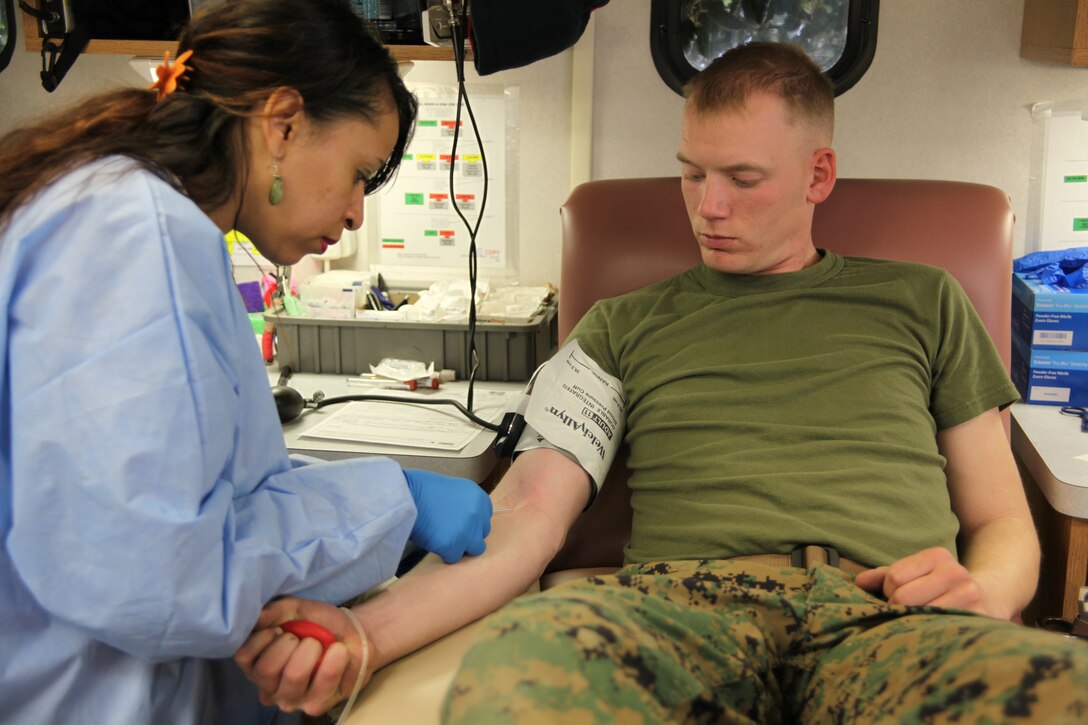 Sgt. Thomas Schade, a landing support specialist with Combat Logistics Company 21, watches as a phlebotomist inserts a needle to draw a pint of blood during a blood drive at Cherry Point’s Naval Health Clinic, March 9. On average, the clinic holds more than 10 blood drives each year.