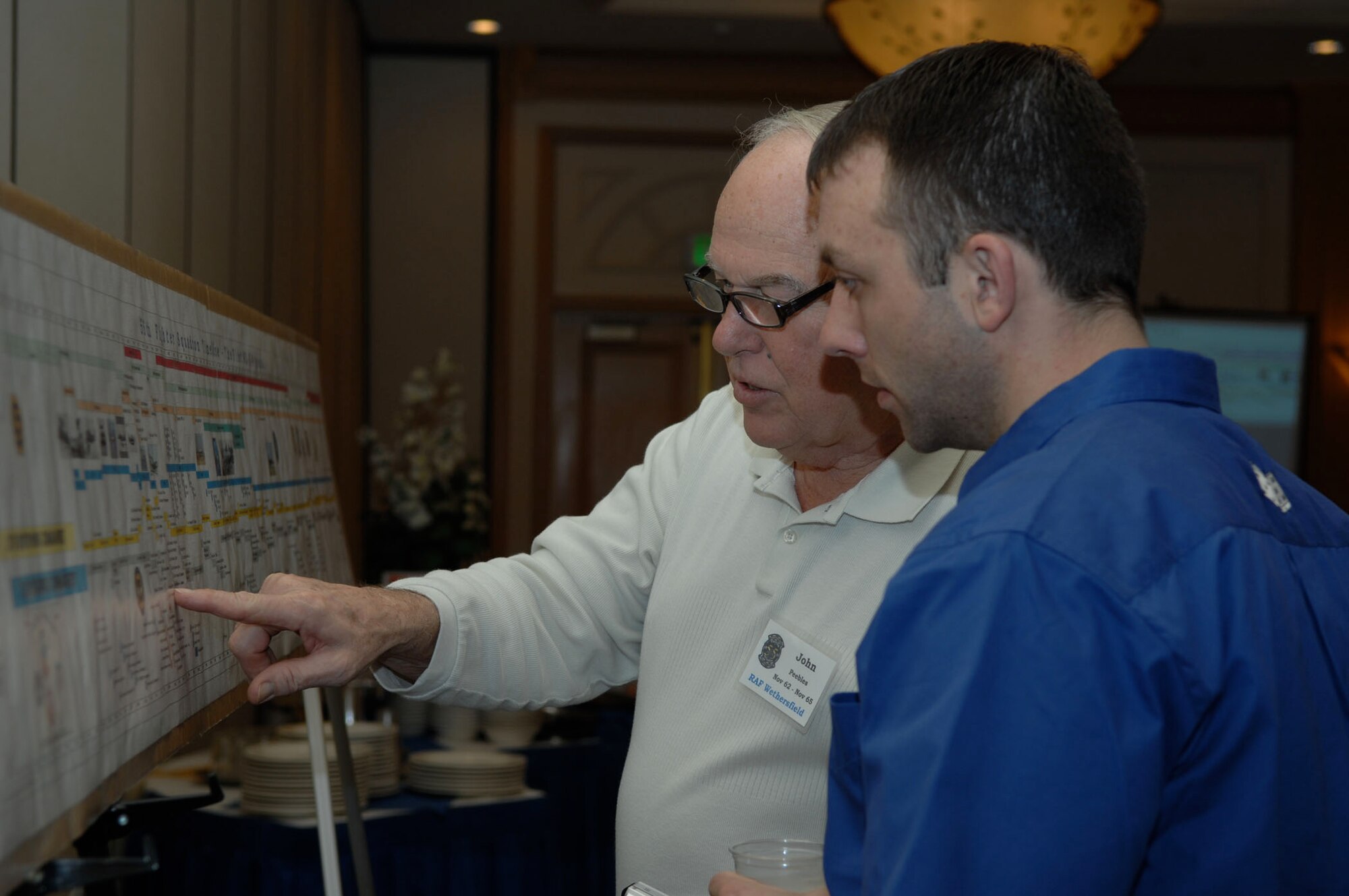 LAS VEGAS -- Retired Air Force Lt. Col. John Peebles, 55th Fighter Squadron "Shooters" alum and president of the 20th Fighter Wing Association, discusses the squadron's history with Capt. Brian Hoose, 55th FS pilot, at a reunion breakfast March 6. Nearly 20 Shooter alumni from every decade since World War II joined current squadron members for a reunion . (U.S. Air Force photo/2nd Lt. Emily Chilson)