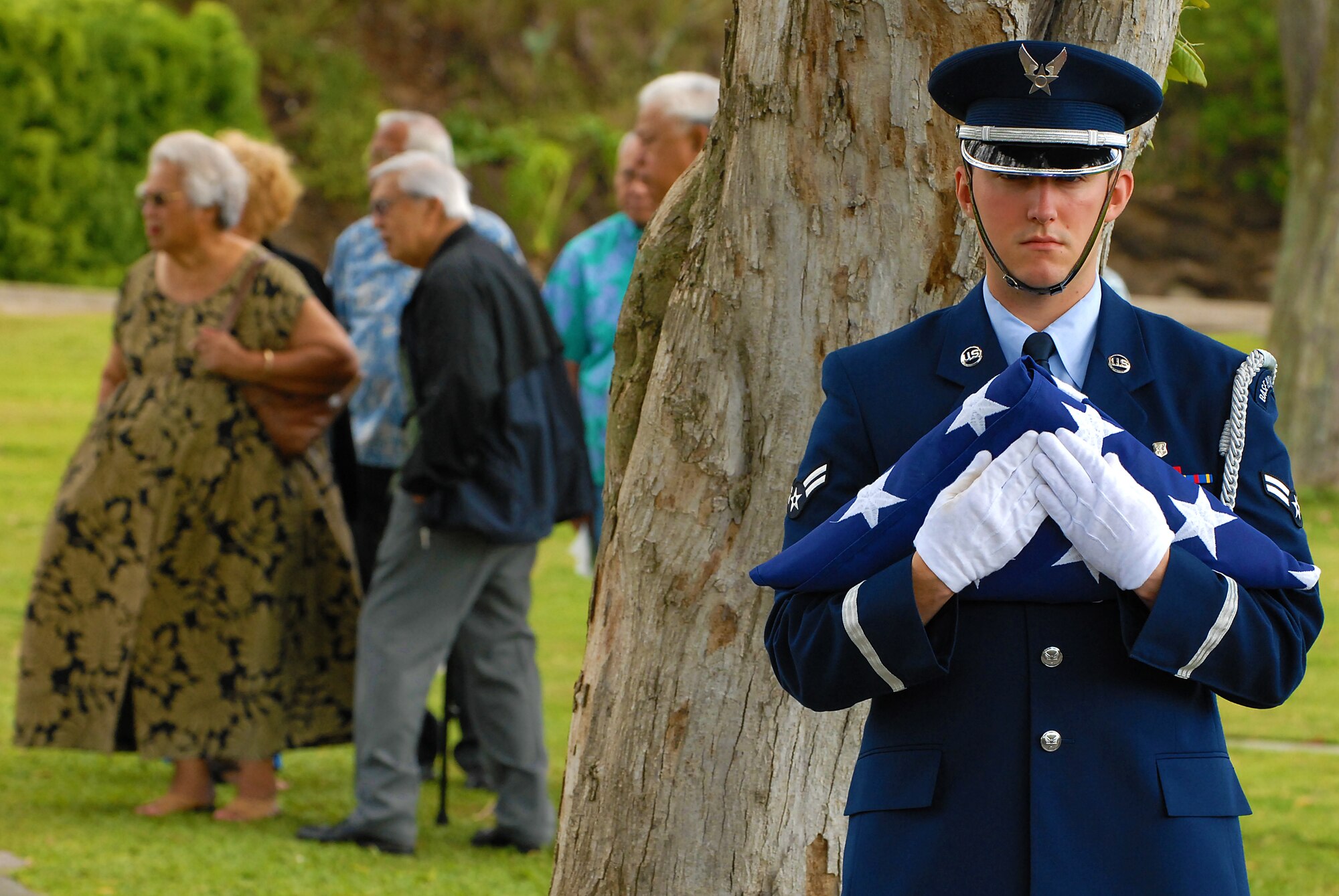 HONOLULU -- Airman 1st Class Alexander Devus, 15th Airlift Wing Honor Guard, holds the American Flag waiting for all family members to arrive prior to a veteran's funeral ceremony at the National Memorial Cemetery of the Pacific March 3. Hickam Honor Guard has the responsibility of representing the United States Air Force throughout the Hawaiian Islands as friends and family gather to pay their final respects to their loved ones that have honorably served their country.(U.S. Air Force photo/Staff Sgt. Mike Meares)