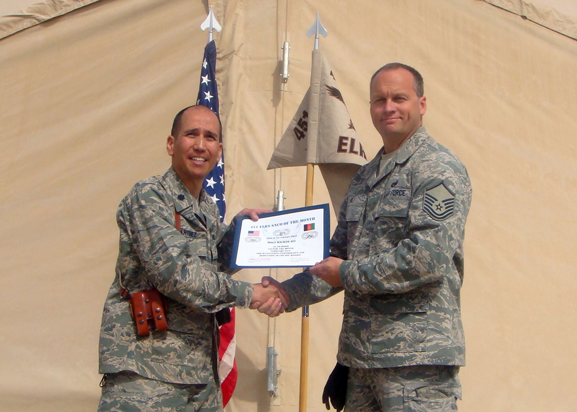 KANDAHAR AIR BASE, AFGHANISTAN  -- Master Sgt. Khalid Ali, shown here accepting the Senior Noncommissioned Officer of the month award from Lt. Col. Steve Martinez, Commander, 451st Expeditionary Logistics Readiness Squadron, during their Commander’s Call in February. 
Master Sgt. Ali is assigned to the 45th Aerial Port Squadron, Travis Air Force Base, and has been deployed to the air base which is located approximately 15 miles from the city of Kandahar. 
This air field was one of the most remote, landlocked and desolate places the U.S. military had ever tried to build a combat base. It made for a perfect hub for the coalition to go on missions into the mountains to battle the Taliban or perform reconstruction projects that range from digging a well for a village to setting the stage for national elections and ratifying a constitution. (U.S. Air Force photo/Airman 1st Class Erica L. Thompson.)                  