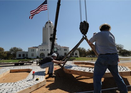 Bill Farrow (left) and Mike Gilligan, both with the 902nd Civil Engineer Squadron, hoist a concrete "O" into place on March 9 as a replacement for some of the historic letters spelling out "Randolph Field." The original letters were installed in the 1930's. (U.S. Air Force photo by David Terry)